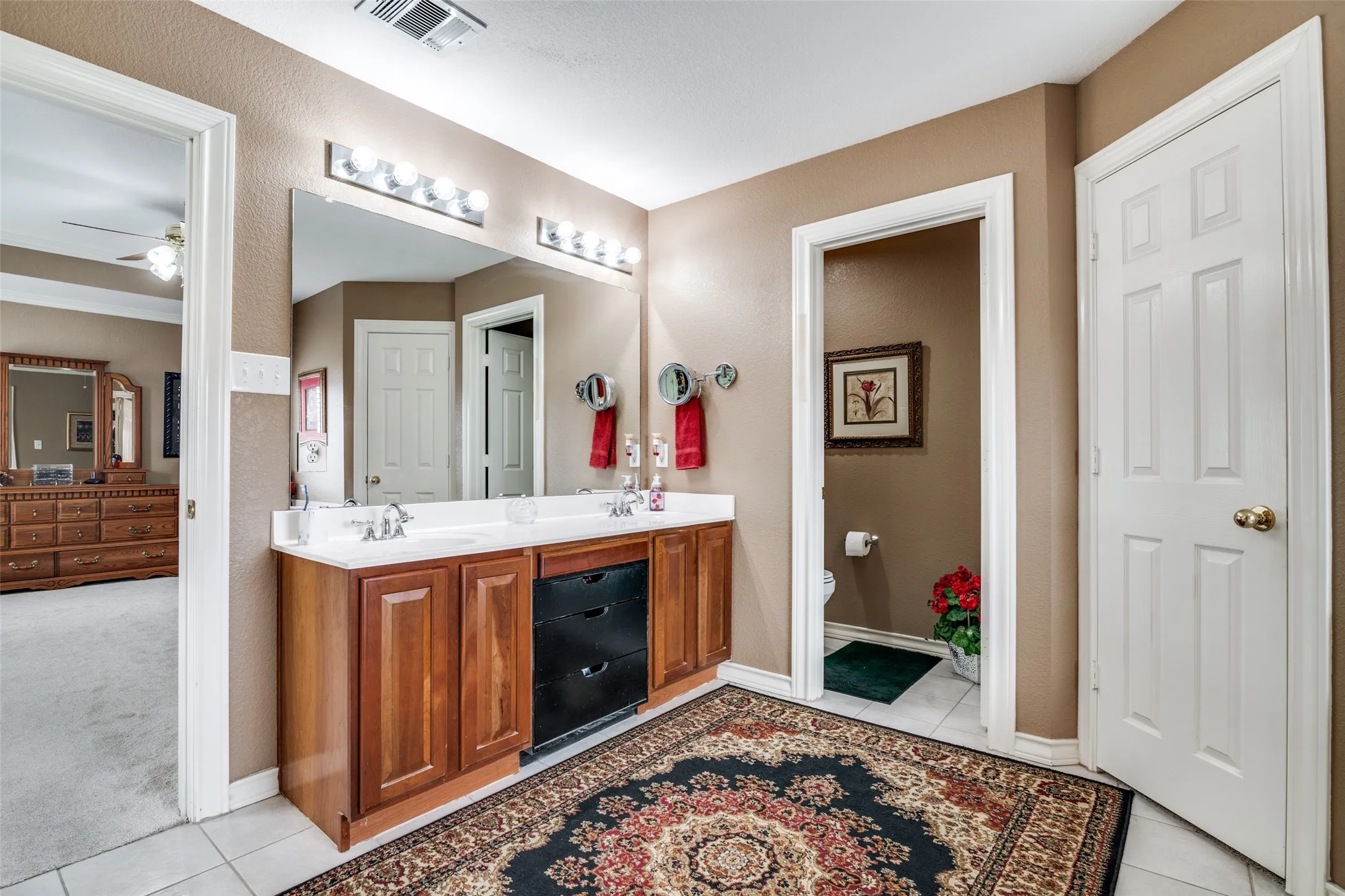Bathroom with double vanity, light tile patterned floors, a ceiling fan, and light carpet