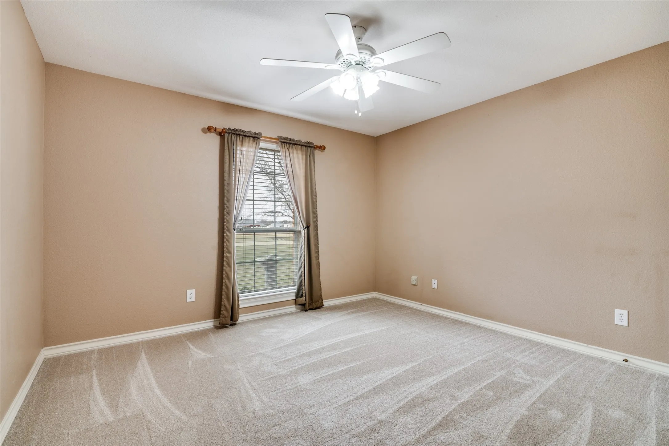Bedroom with a ceiling fan and light colored carpet