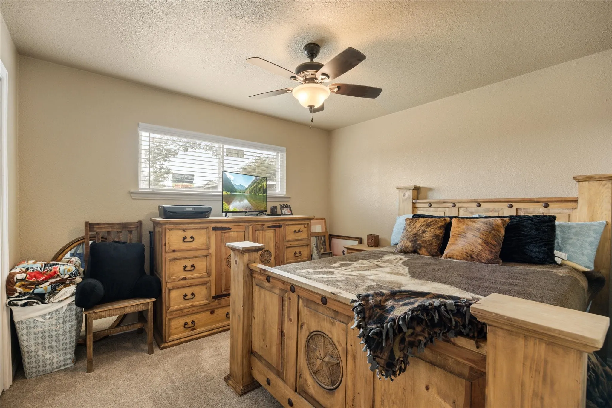 Bedroom with a textured ceiling, light colored carpet, and ceiling fan