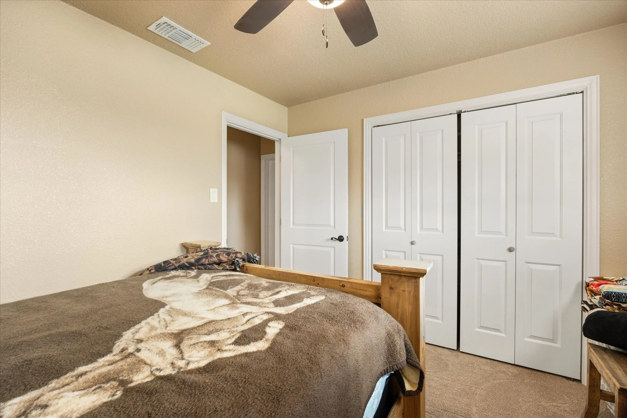 Bedroom featuring a textured ceiling, light colored carpet, a closet, and ceiling fan