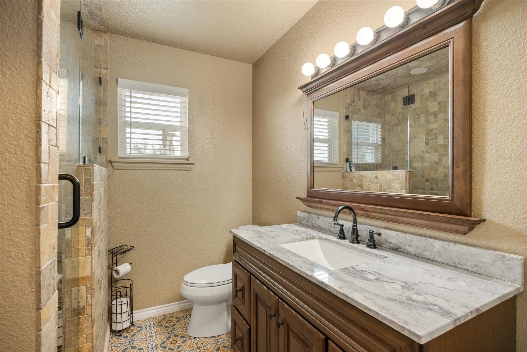 Bathroom featuring vanity, toilet, walk in shower, and tile patterned flooring