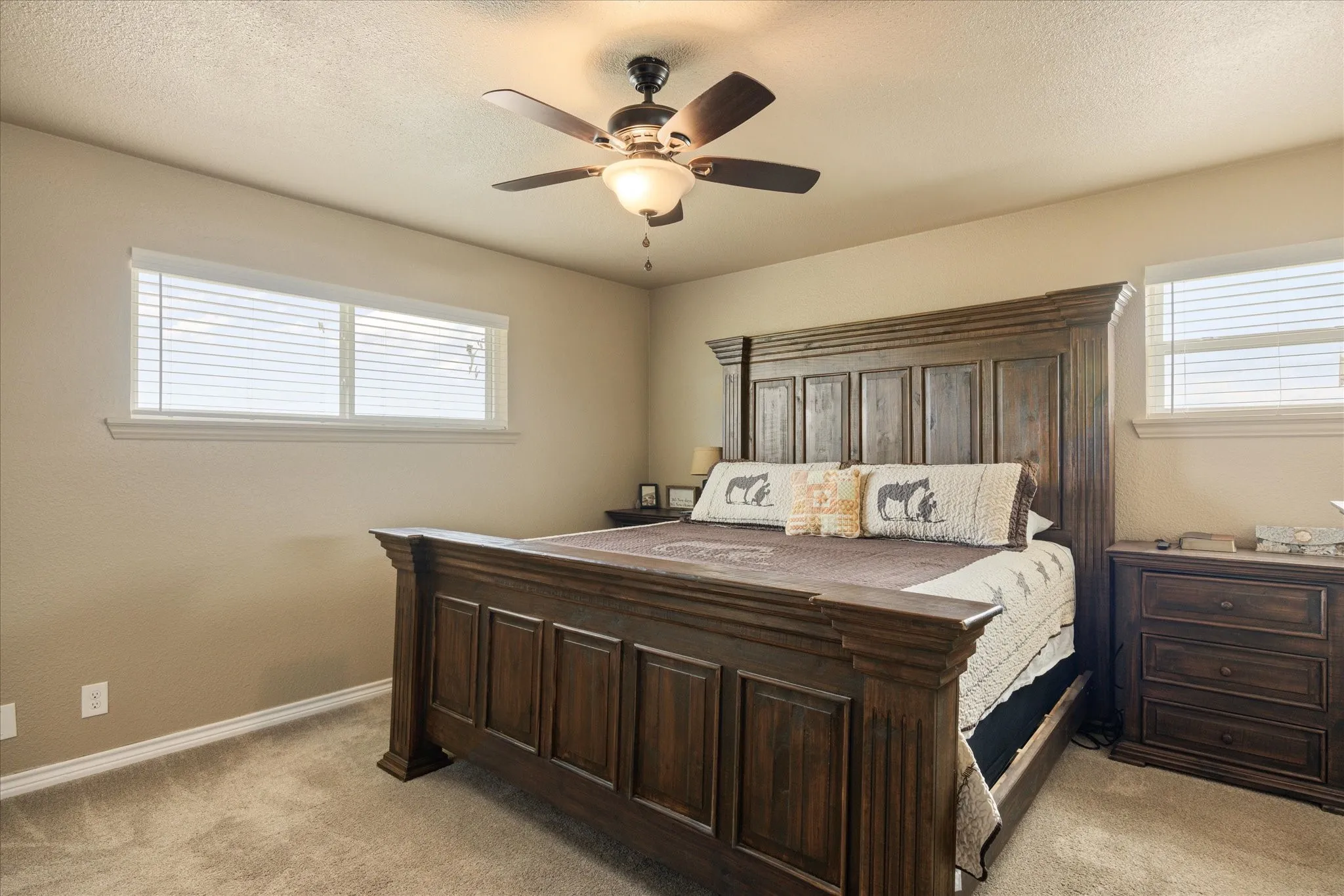 Bedroom featuring a textured ceiling, light carpet, multiple windows, and ceiling fan