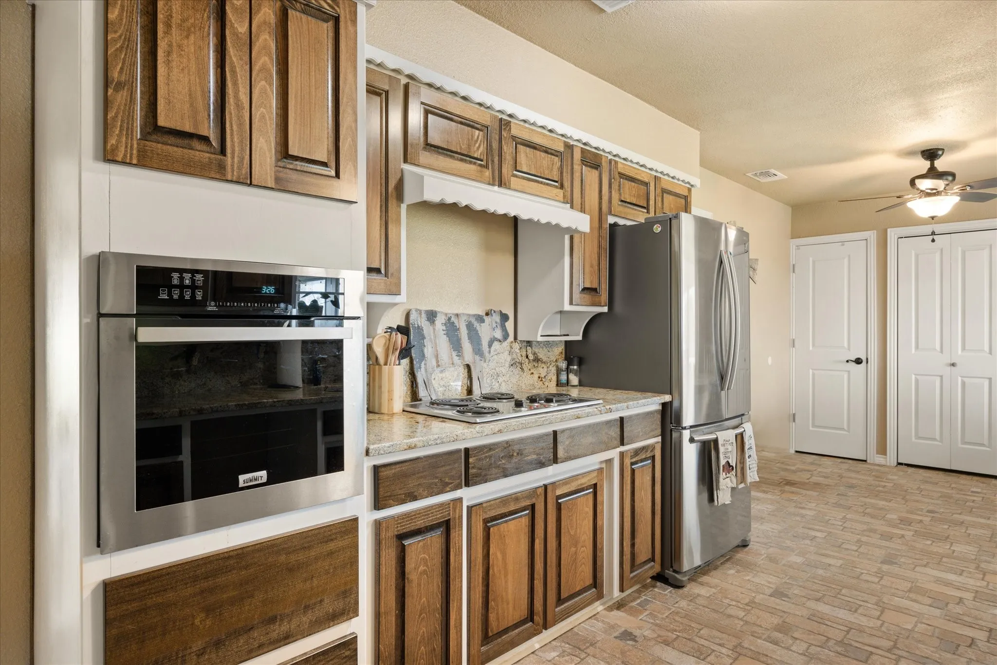 Kitchen featuring a textured ceiling, stainless steel appliances, and ceiling fan
