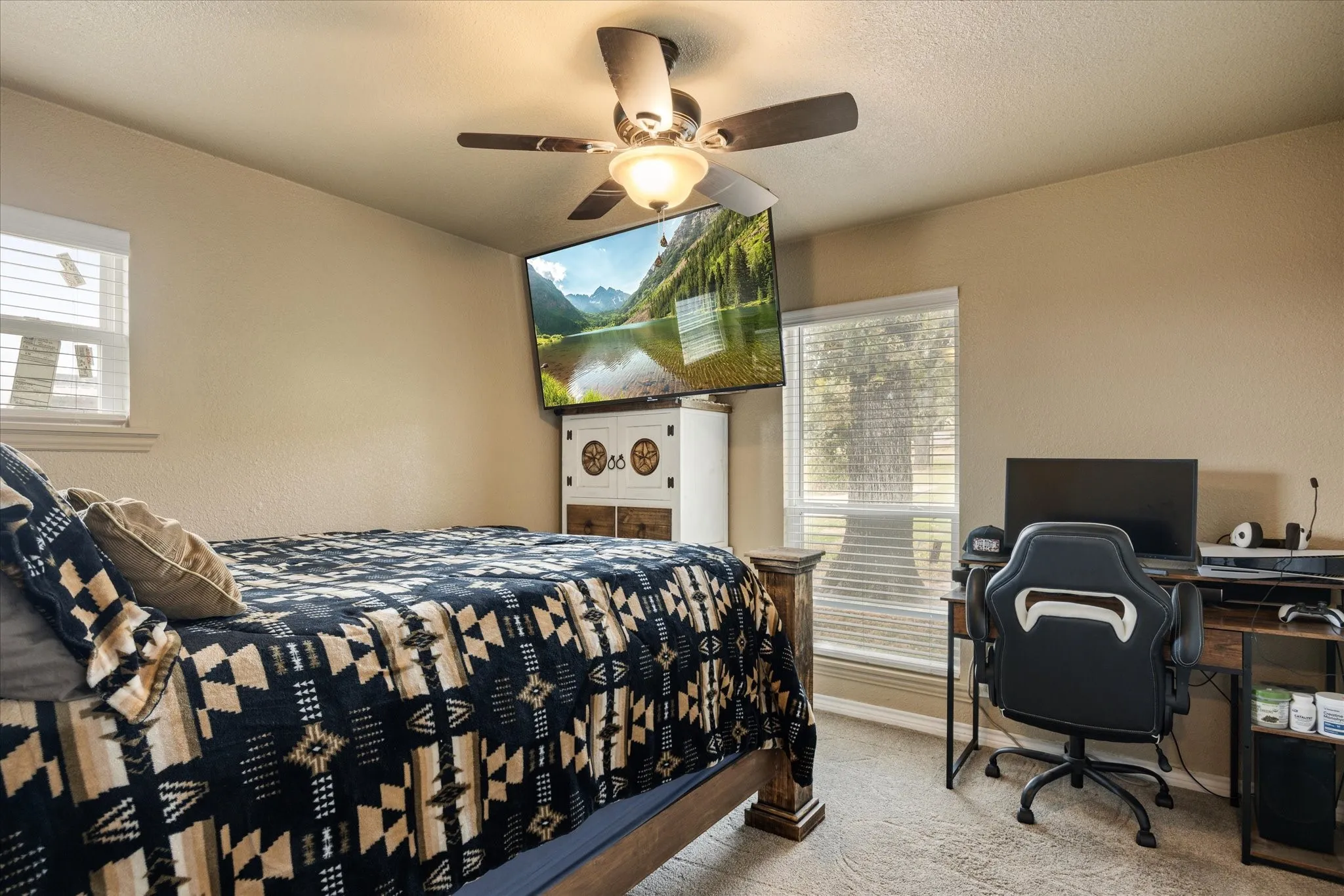 Bedroom featuring ceiling fan, multiple windows, and light colored carpet