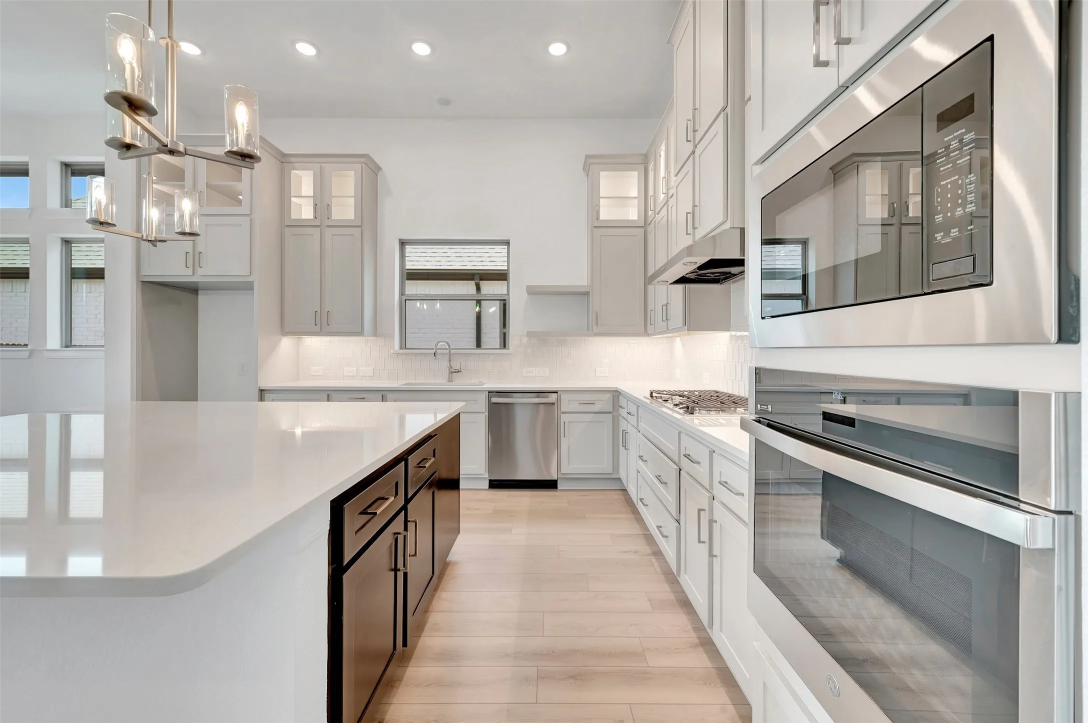Kitchen featuring light wood-finish flooring, a central island with a white countertop and dark cabinetry, and perimeter white cabinetry with white countertops