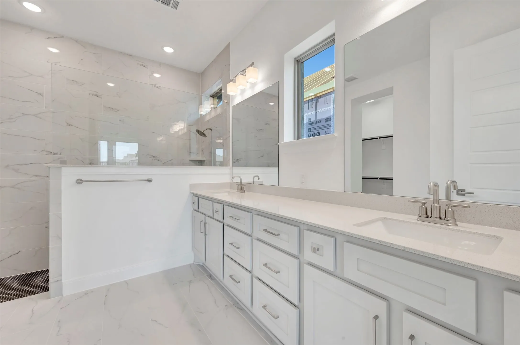 Spacious bathroom featuring a dual vanity with undermount sinks, stone countertops, and extensive cabinetry