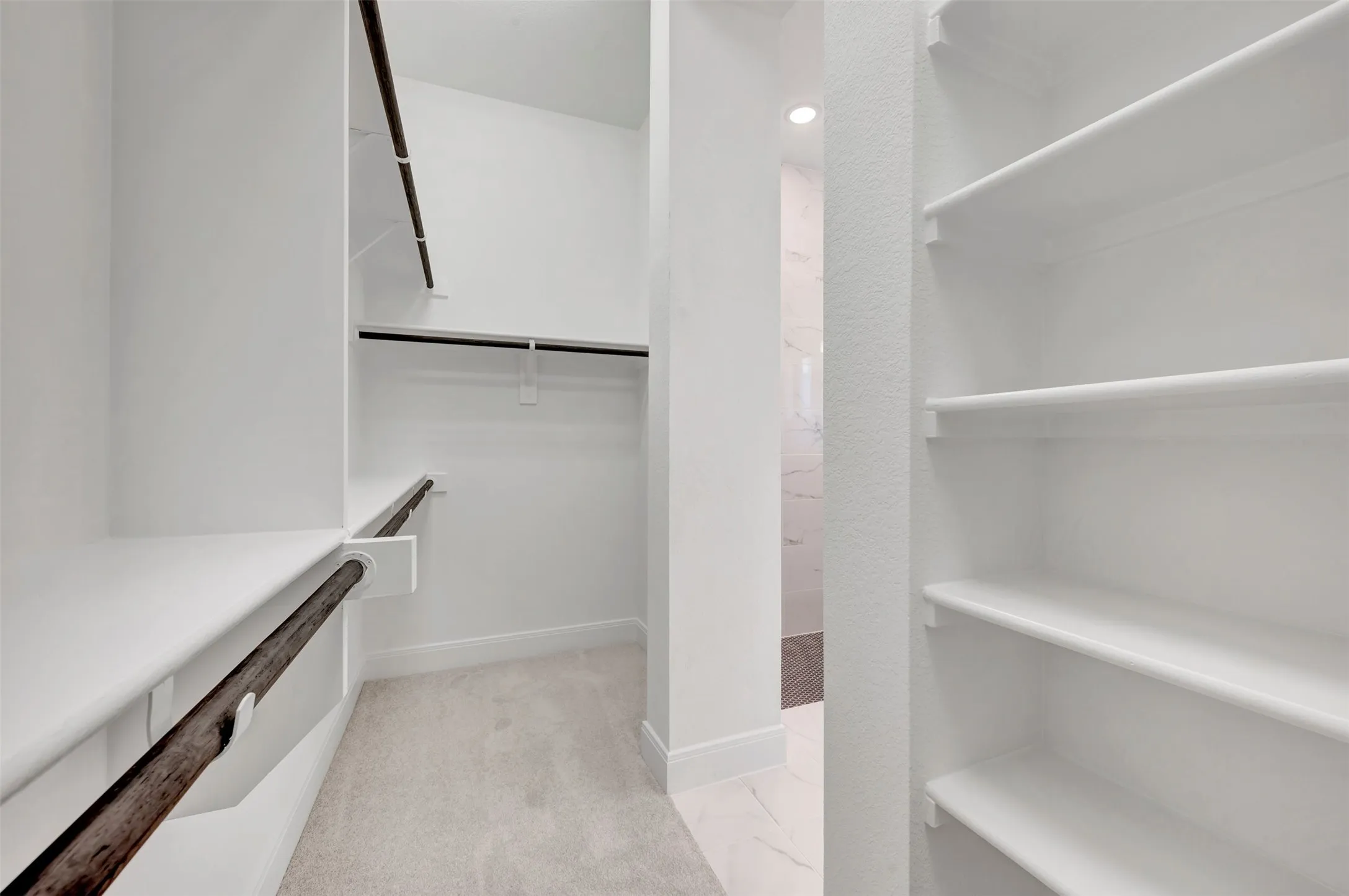 Walk-in closet featuring multiple hanging rods and built-in shelving