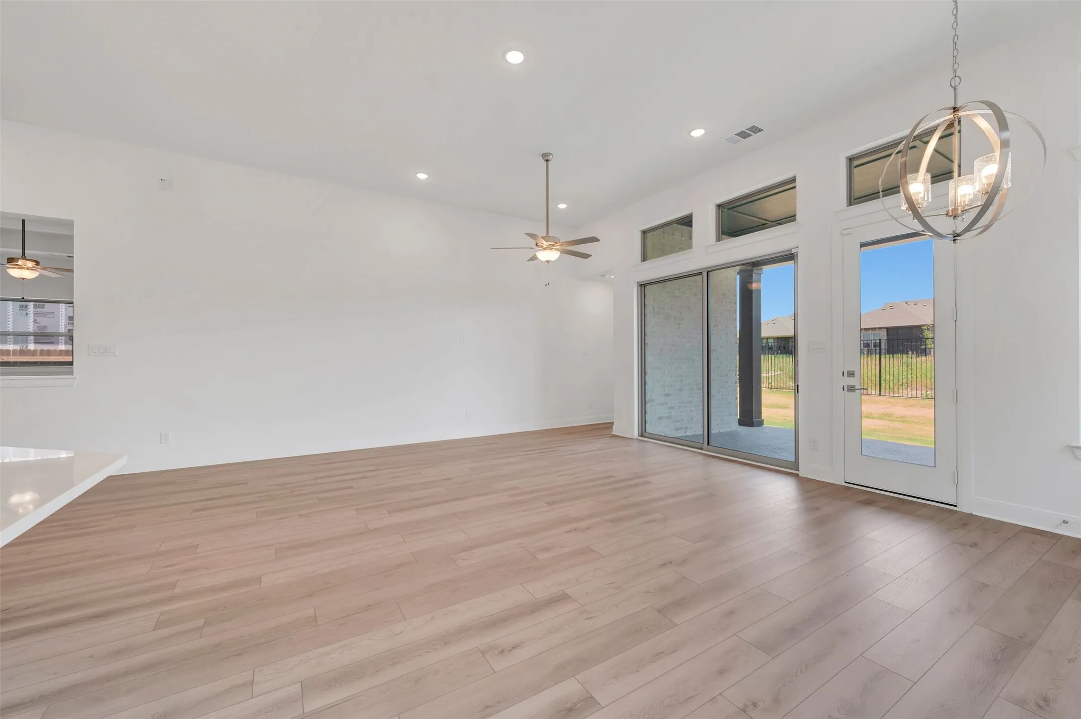 Open-concept living space featuring wood-finish flooring, recessed lighting, and a modern orb chandelier