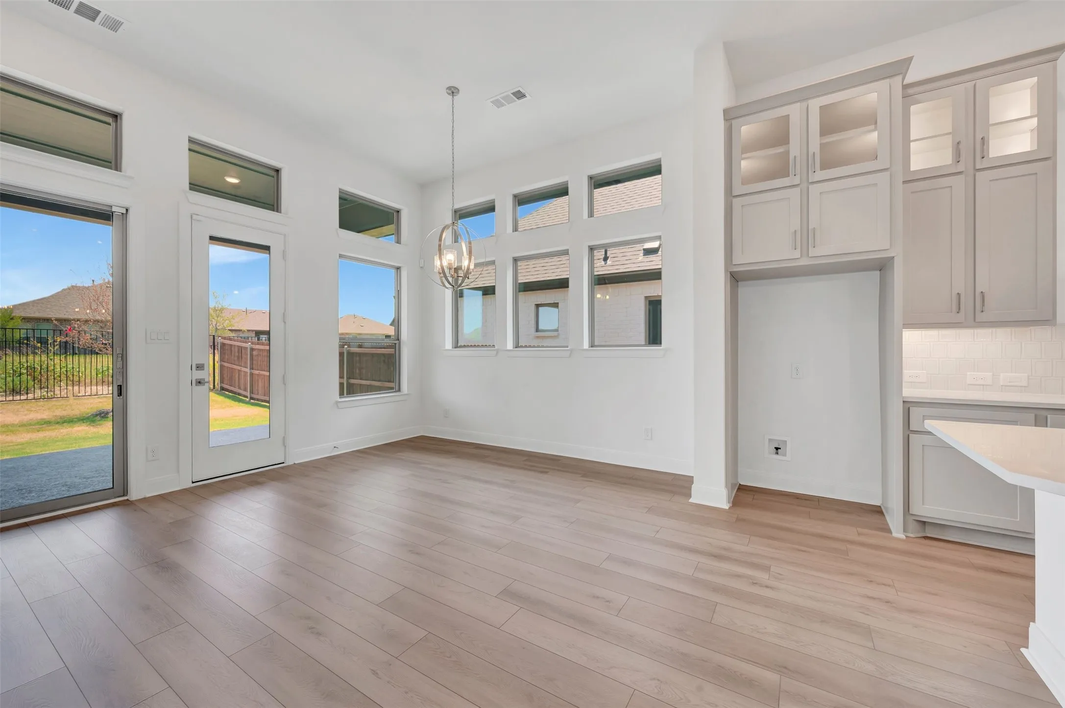 Open-concept area featuring wood-finish flooring, a contemporary chandelier, multiple transom windows, a sliding glass door, and a glass-paneled exterior door