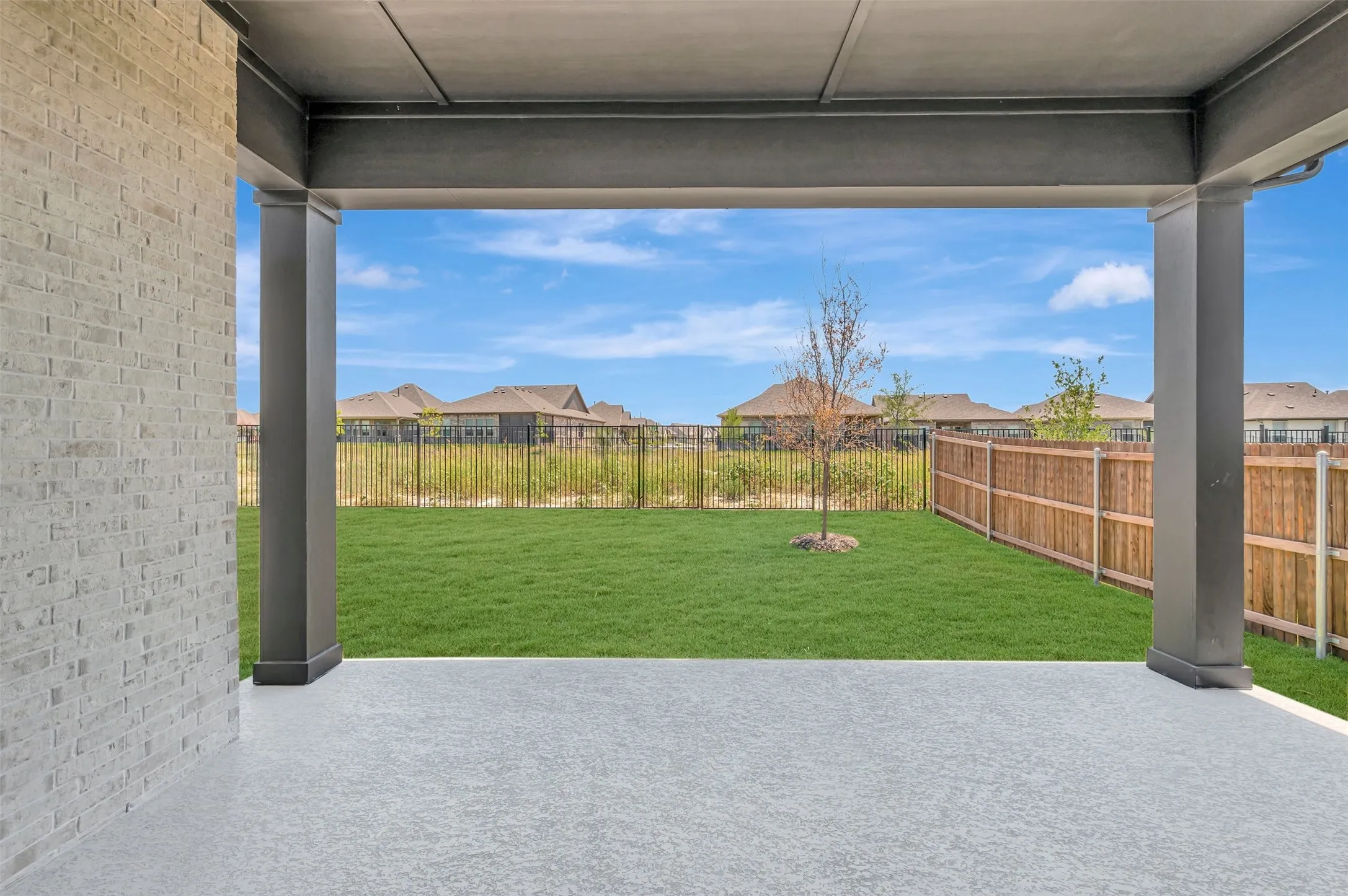 Covered patio with a textured concrete surface and dark support columns