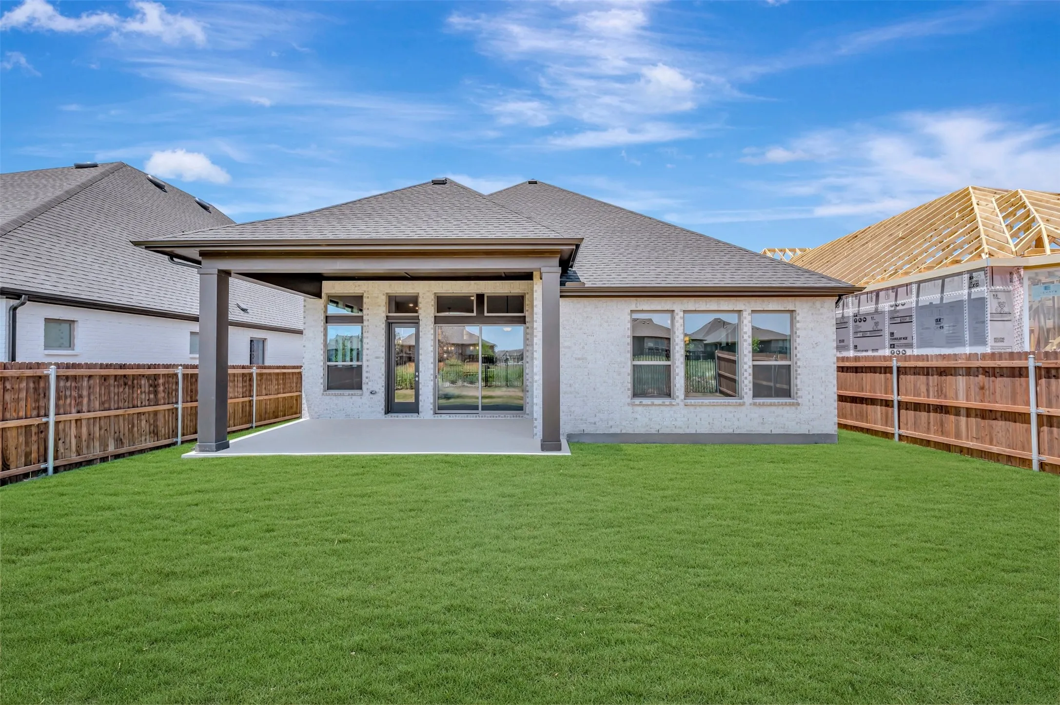 Expansive backyard featuring a manicured lawn, full fencing, and a covered patio with recessed lighting