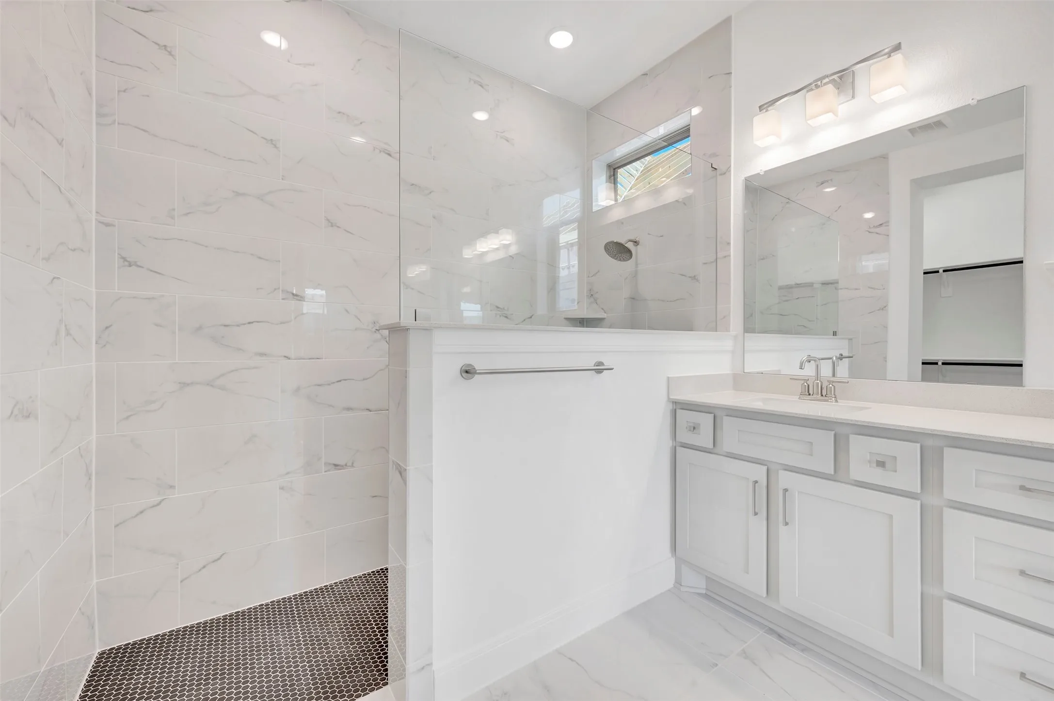 Spacious bathroom featuring a glass-enclosed shower with large format tile walls and a hexagonal tile floor