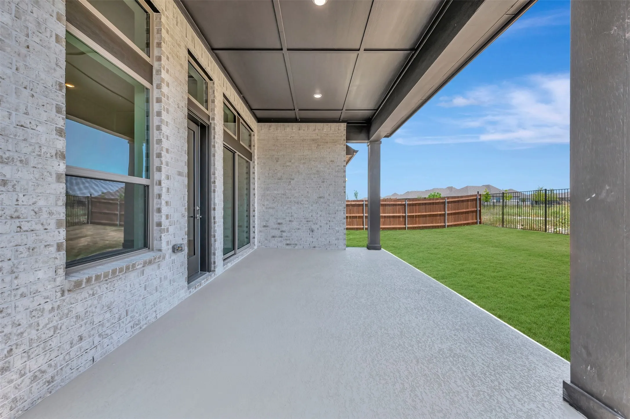 Expansive covered patio featuring a textured concrete floor and recessed lighting