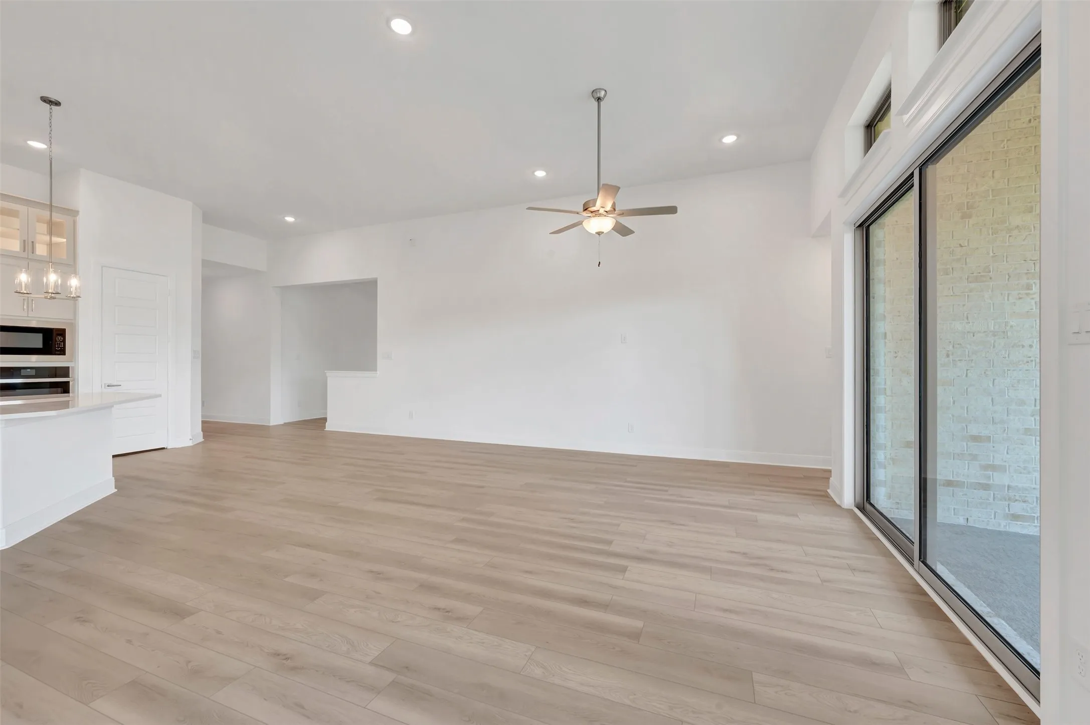 Open-concept living area featuring light wood-finish flooring, recessed lighting, and a ceiling fan