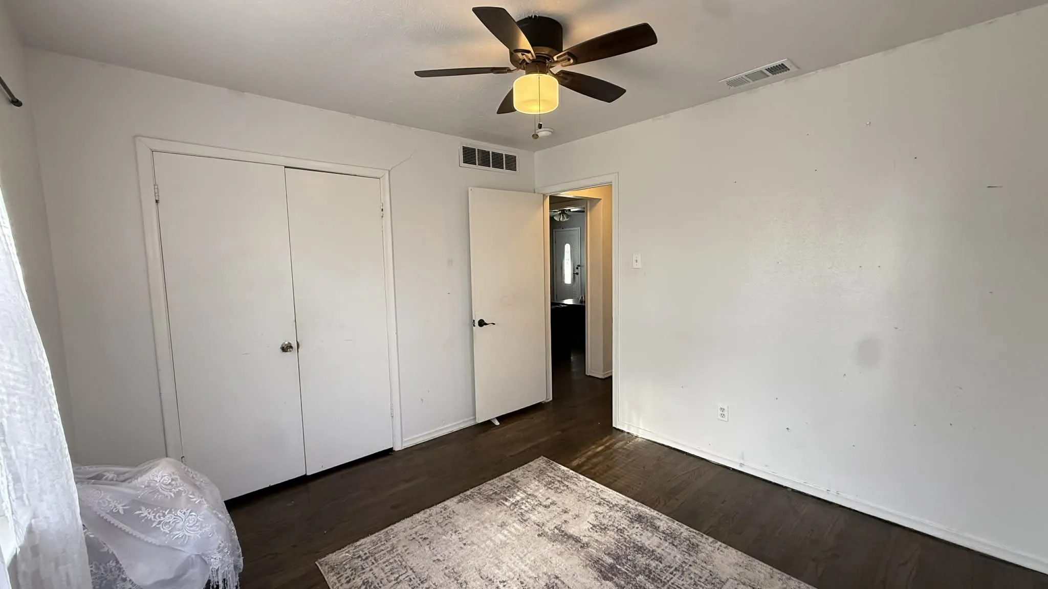 Unfurnished bedroom with a ceiling fan, a closet, and dark wood finished floors