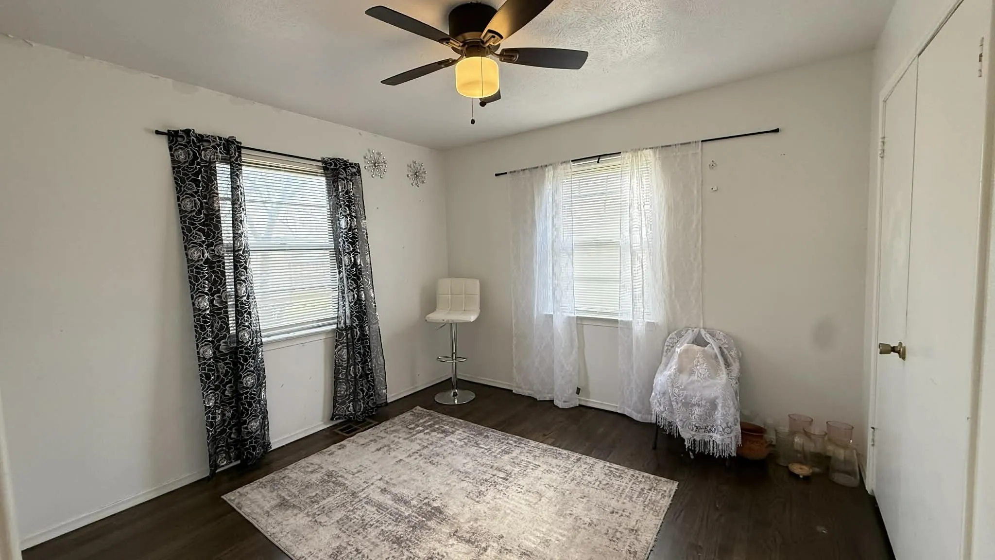 Unfurnished room featuring dark wood-type flooring, ceiling fan, and healthy amount of natural light