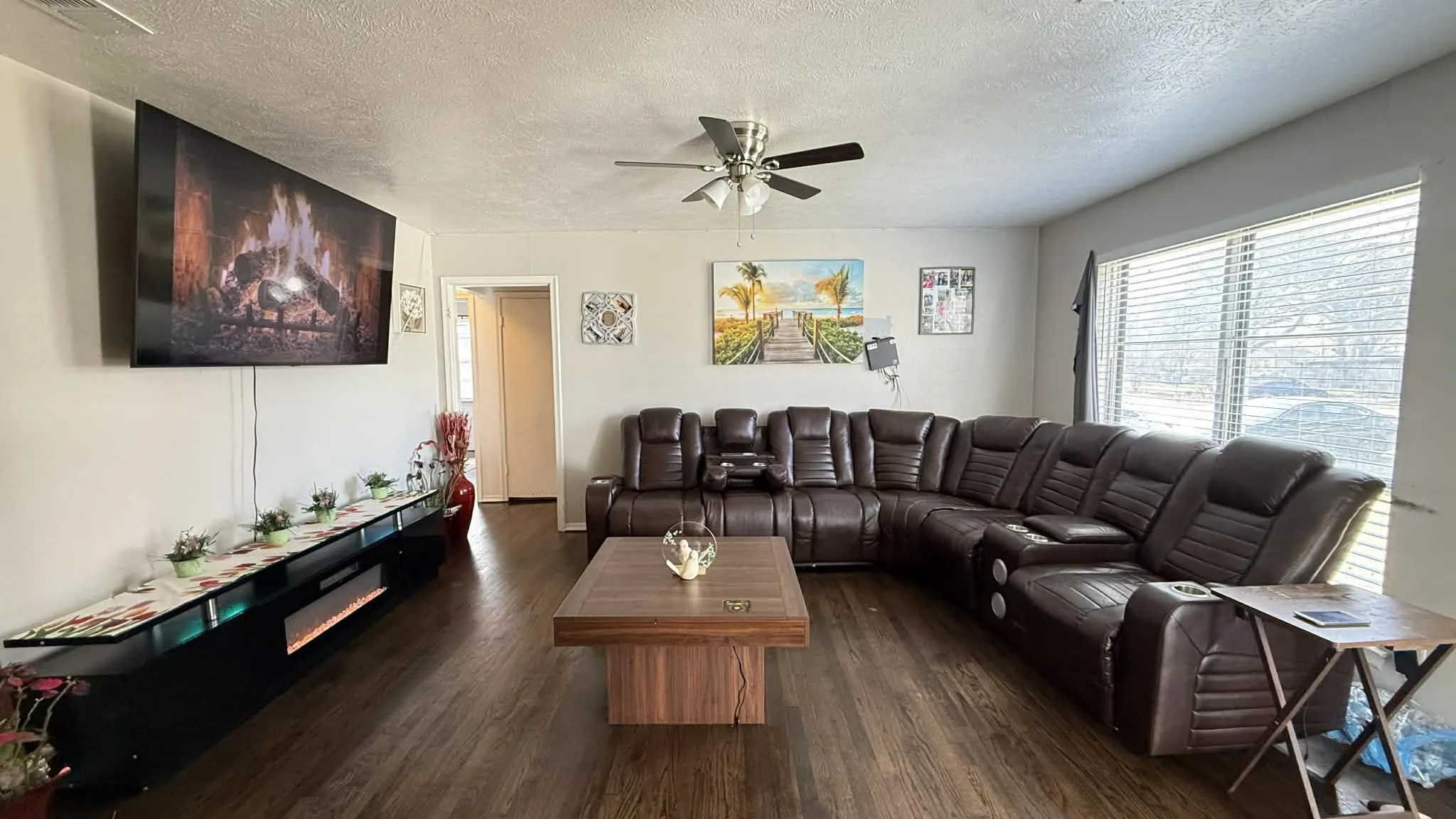 Living room with dark wood-style flooring, a textured ceiling, and a ceiling fan