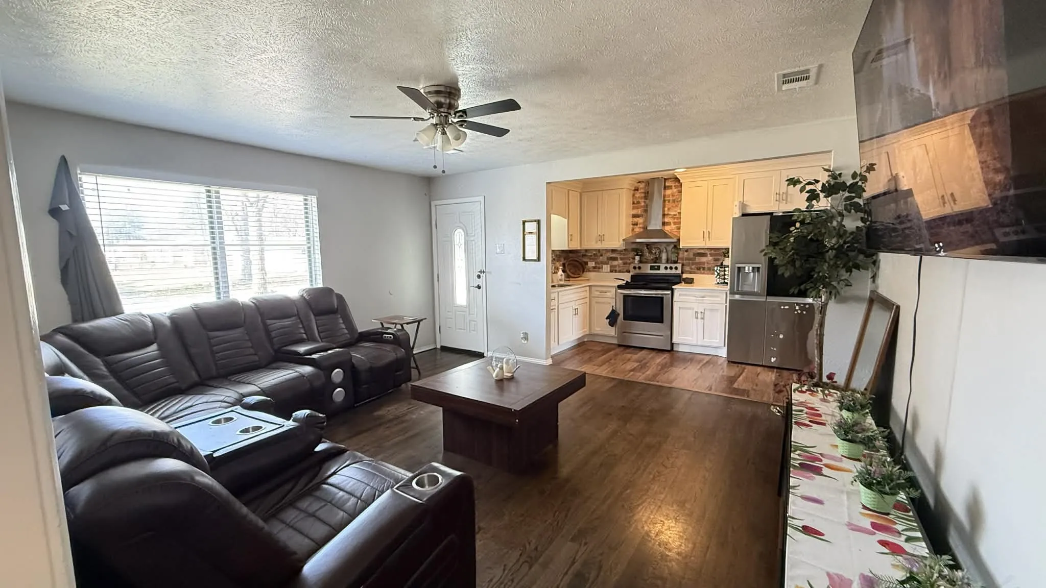 Living area featuring dark wood-style floors, a textured ceiling, and ceiling fan