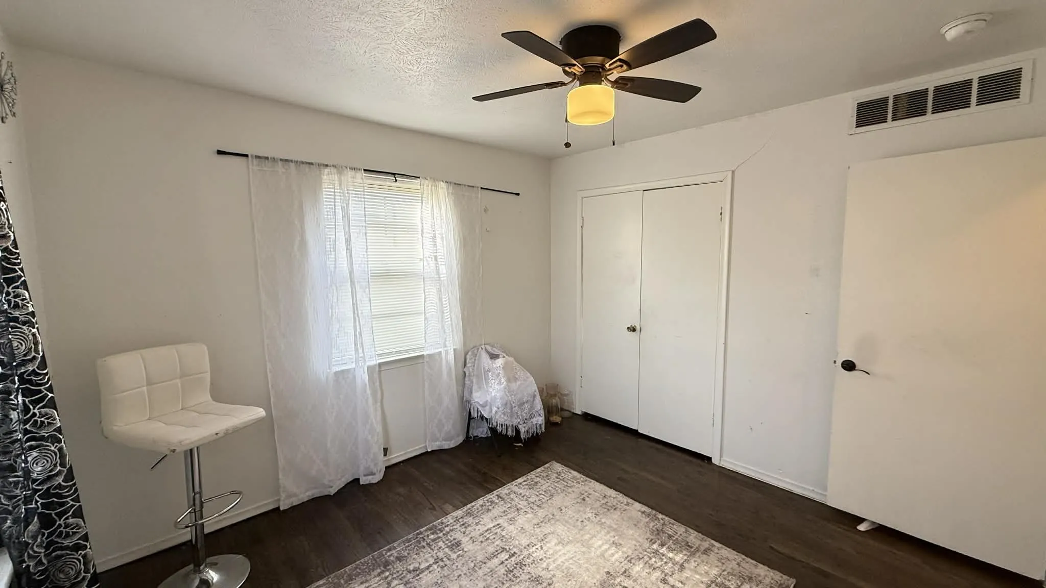 Bedroom featuring dark wood finished floors, ceiling fan, a closet, and a textured ceiling