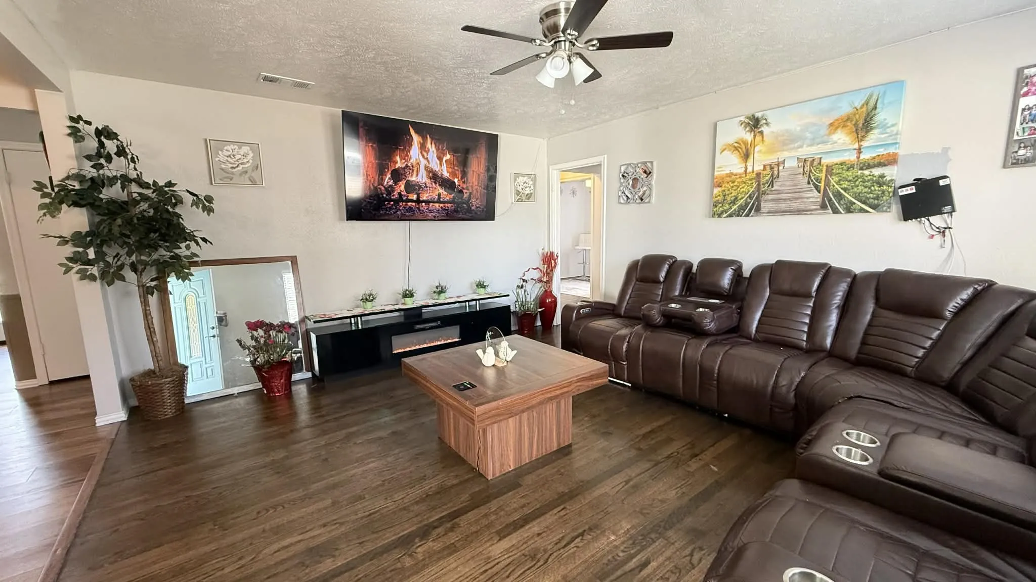 Living room with a ceiling fan, a textured ceiling, and dark wood finished floors