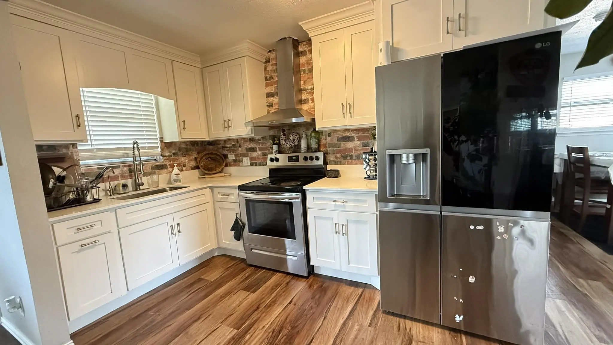 Kitchen featuring stainless steel appliances, white cabinets, dark wood-type flooring, and light stone countertops