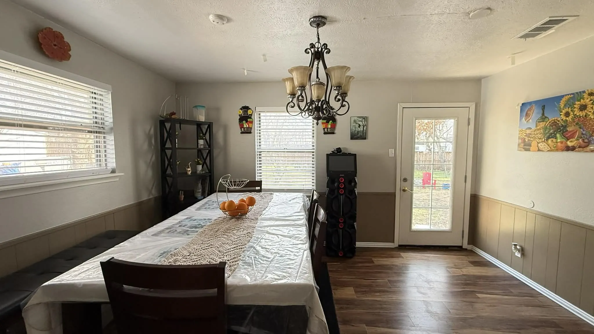Dining area featuring wainscoting, dark wood finished floors, wooden walls, a chandelier, and a textured ceiling