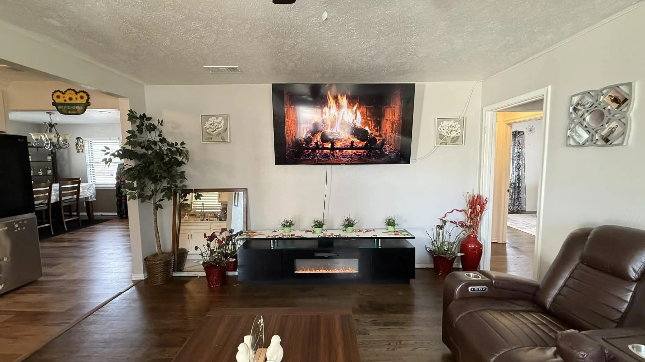 Living area with dark wood-style flooring, a textured ceiling, and a glass covered fireplace