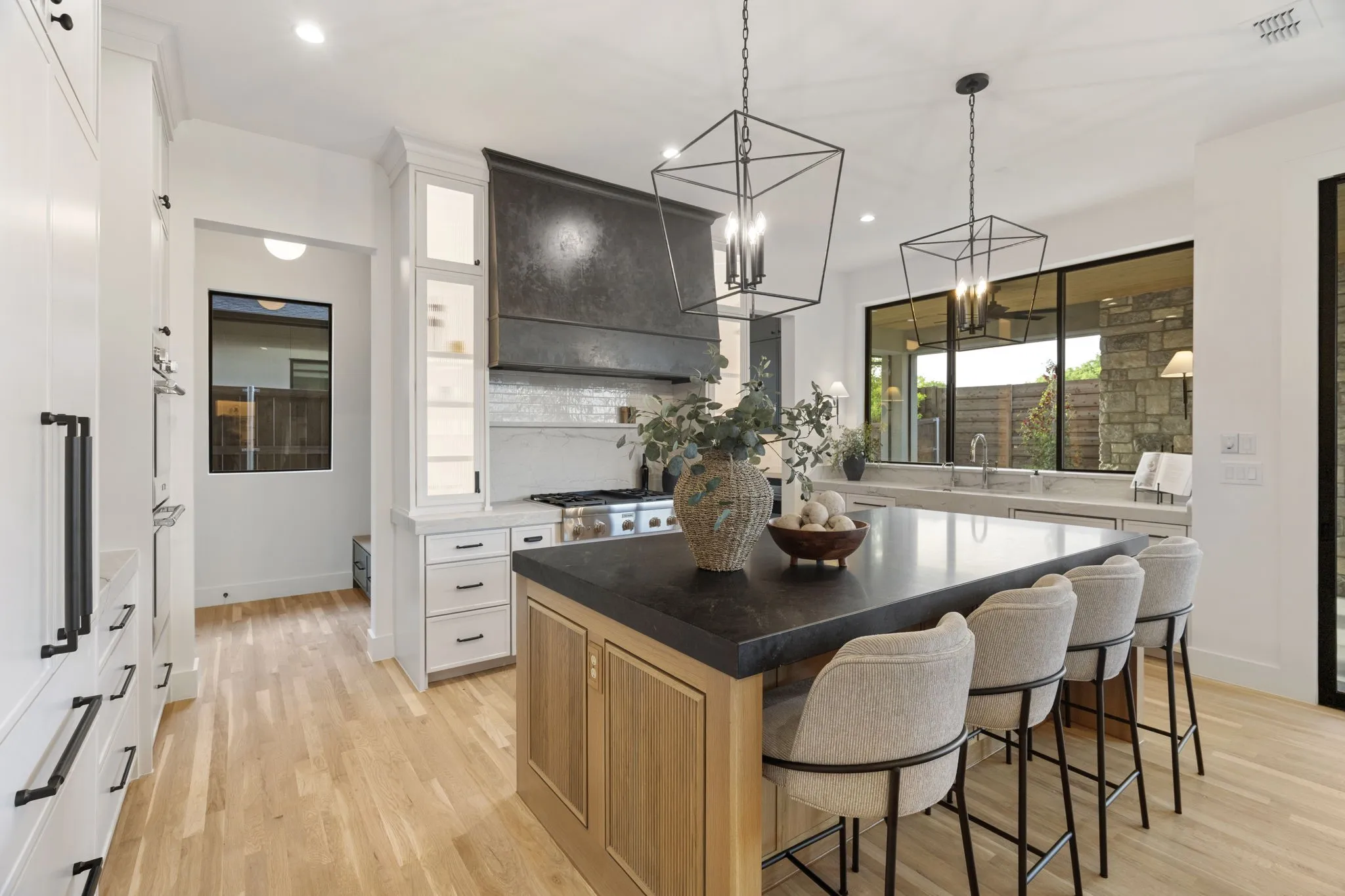Two tone kitchen featuring a breakfast bar area, a center island, light wood-style floors, two tone color scheme, and dark stone countertops