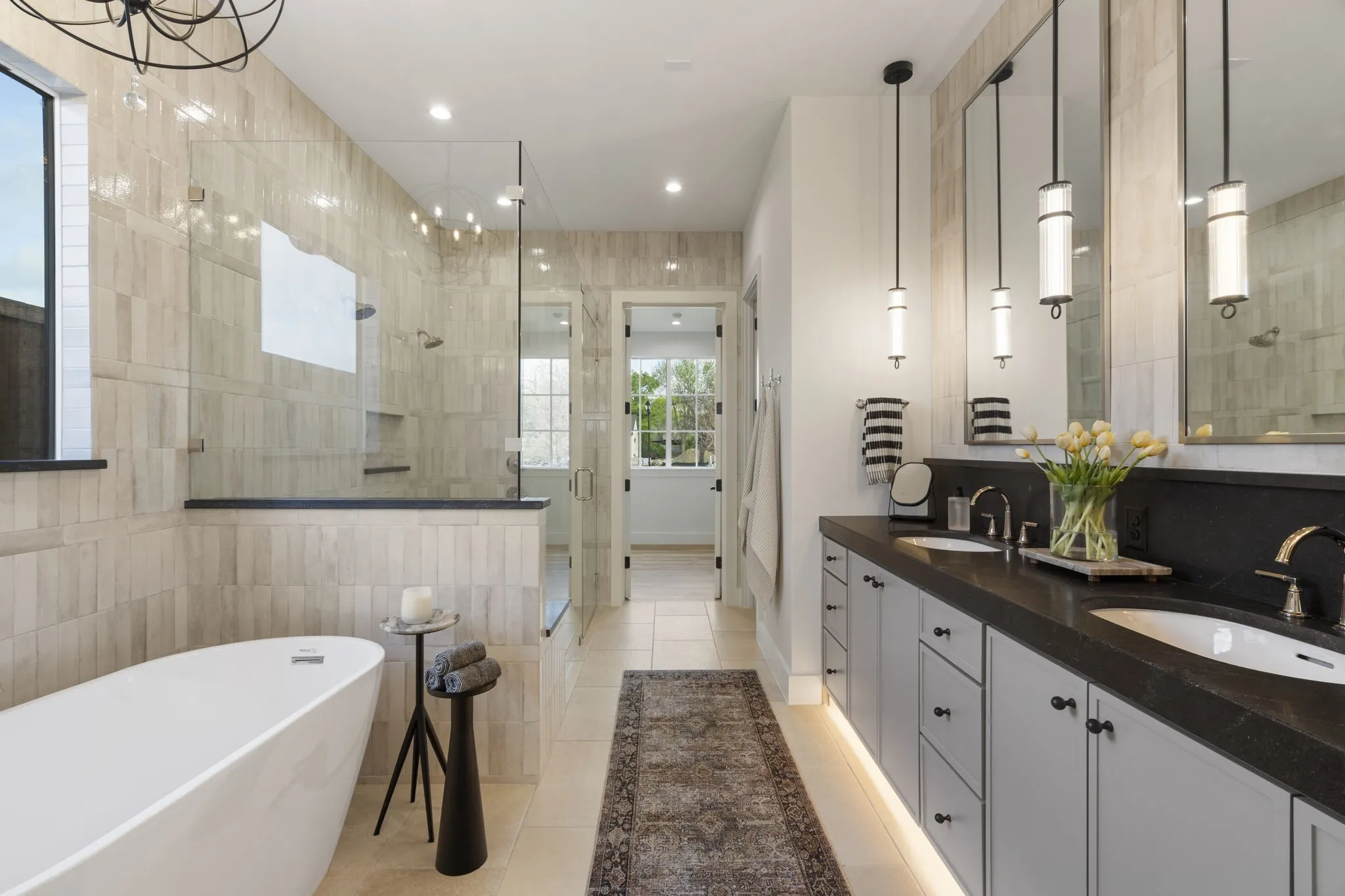Full bathroom with tile walls, double vanity, a shower stall, a freestanding tub, and light tile patterned floors