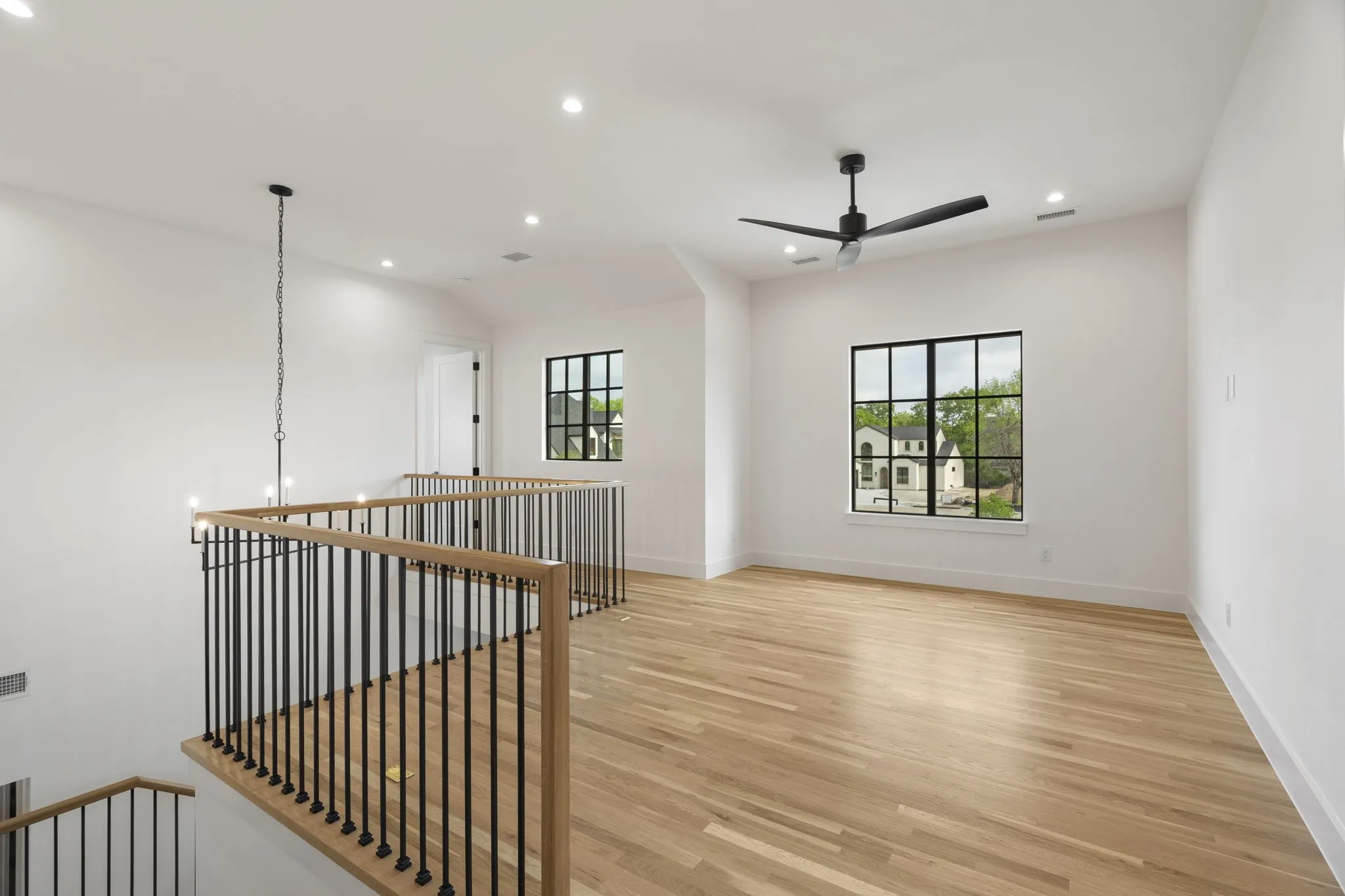 Upstairs Loft with light wood-style flooring, ceiling fan, and suspended lighting