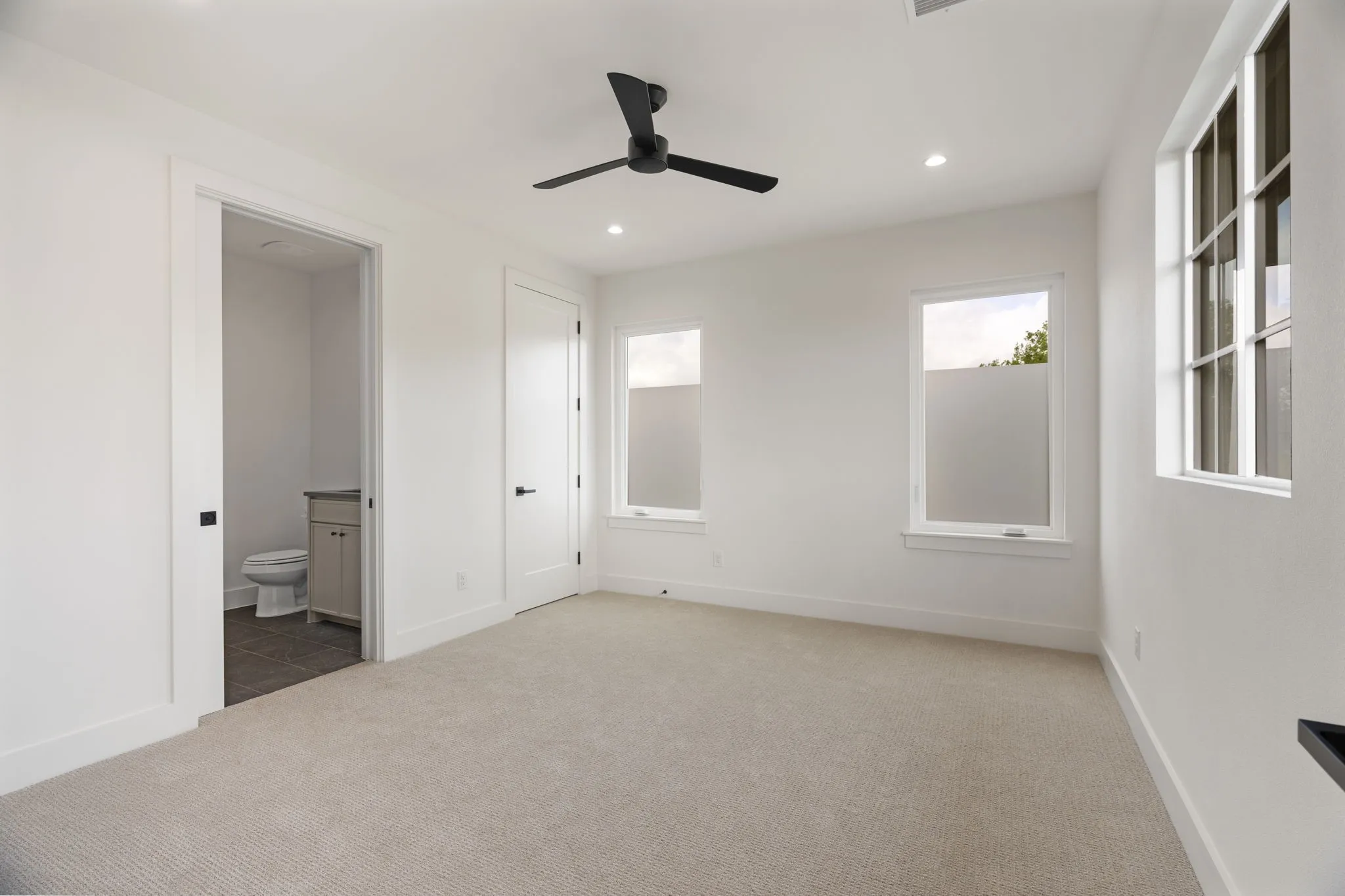 Unfurnished bedroom featuring carpet floors, recessed lighting, ceiling fan, and ensuite bath