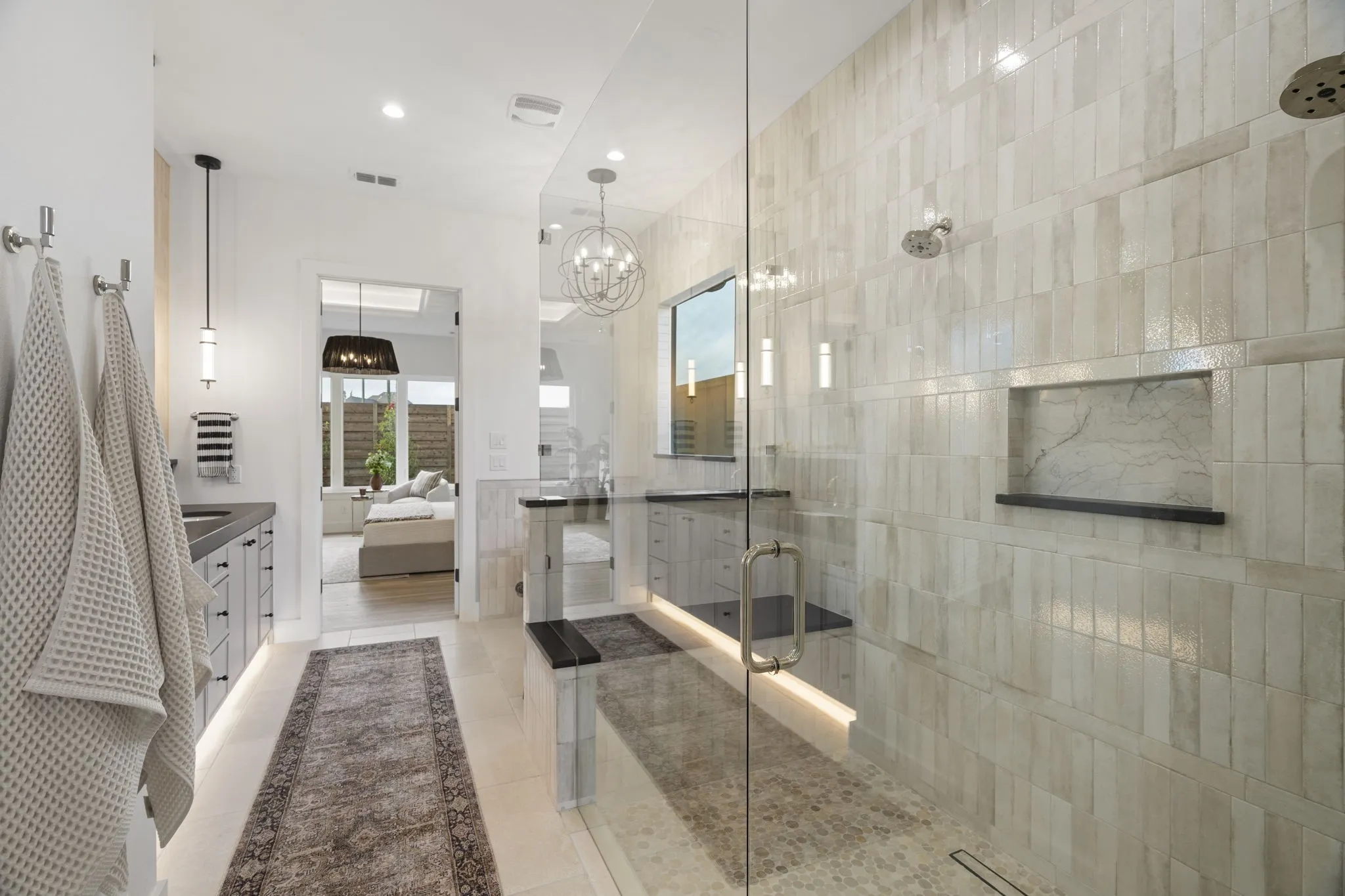 Bathroom featuring connected bathroom, a shower stall, two vanities, and suspended lighting