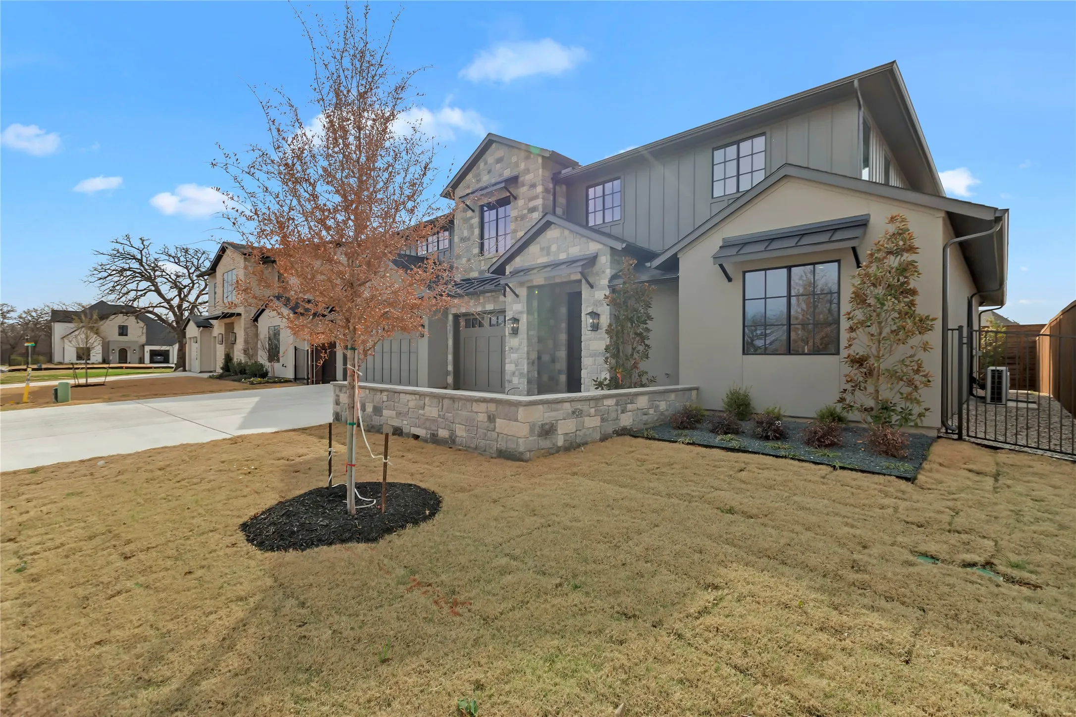 View of front of home featuring a front lawn, driveway, board and batten siding, a gate, and a garage