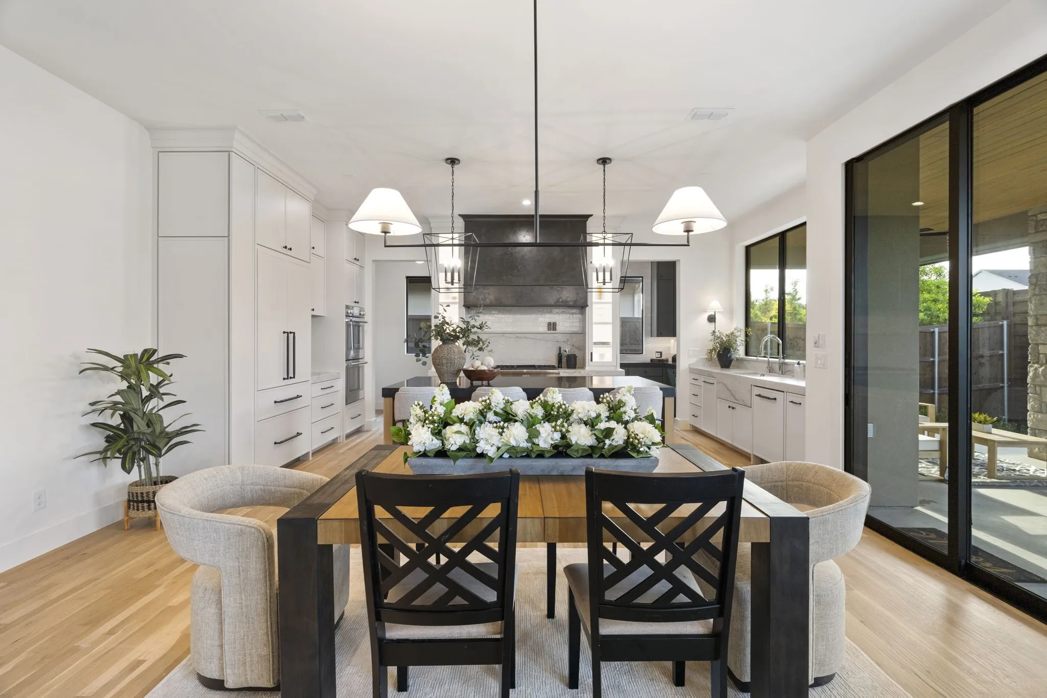 Kitchen with a center island, light wood finished floors, white cabinets, and decorative light fixtures