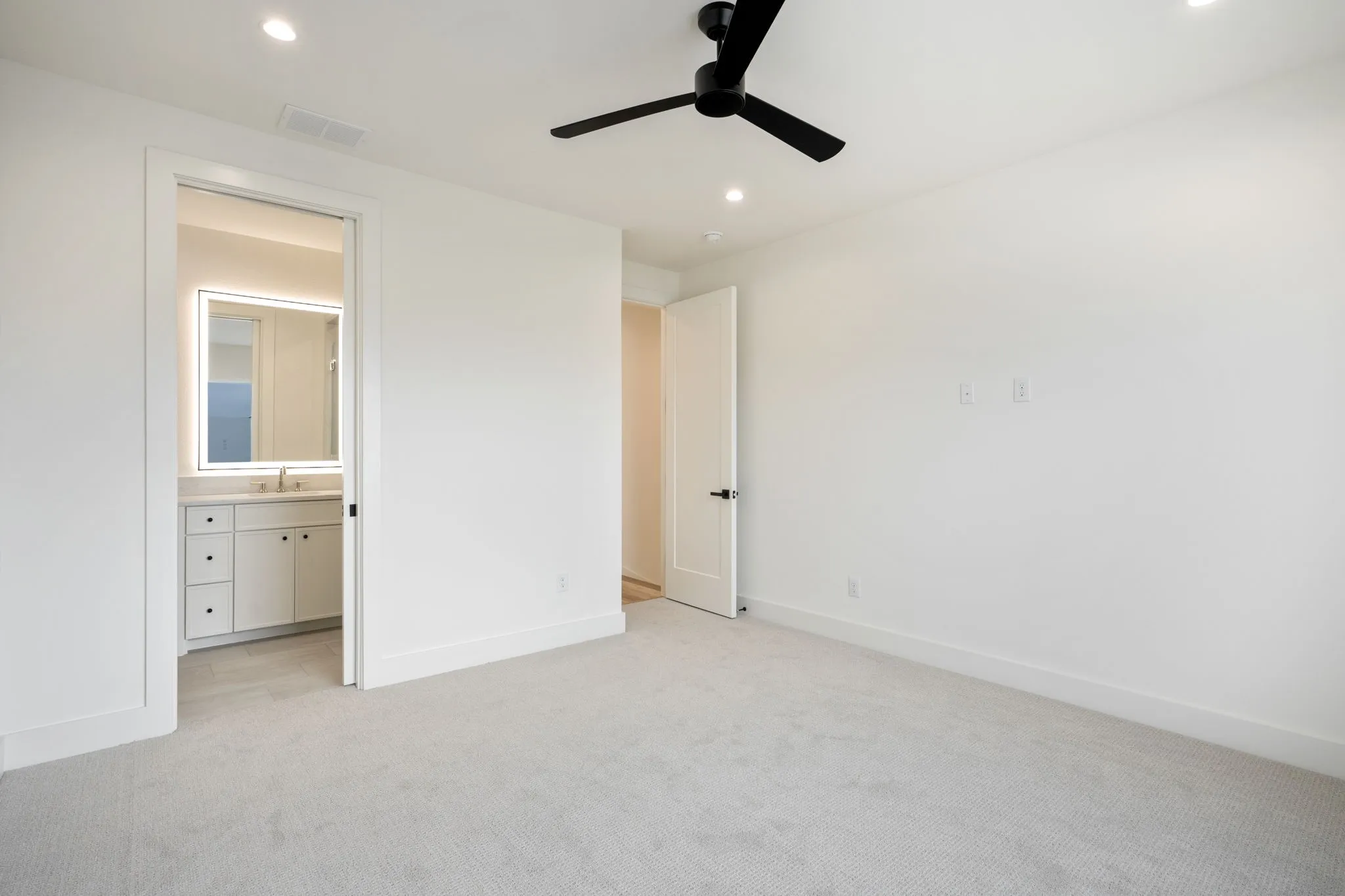 Unfurnished bedroom with light carpet, recessed lighting, ceiling fan, and connected bathroom