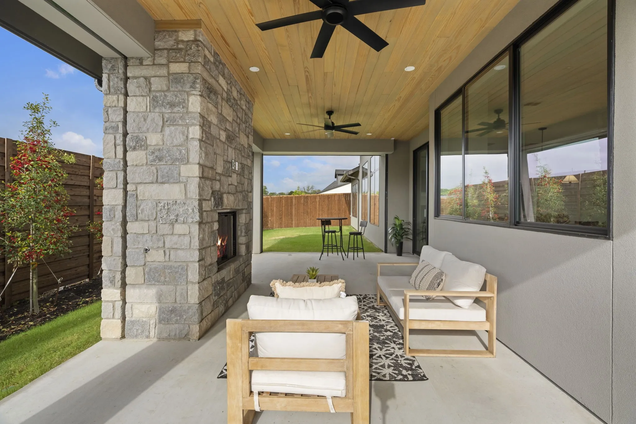 Fenced backyard featuring a patio area, an outdoor living space with a fireplace, and a ceiling fan