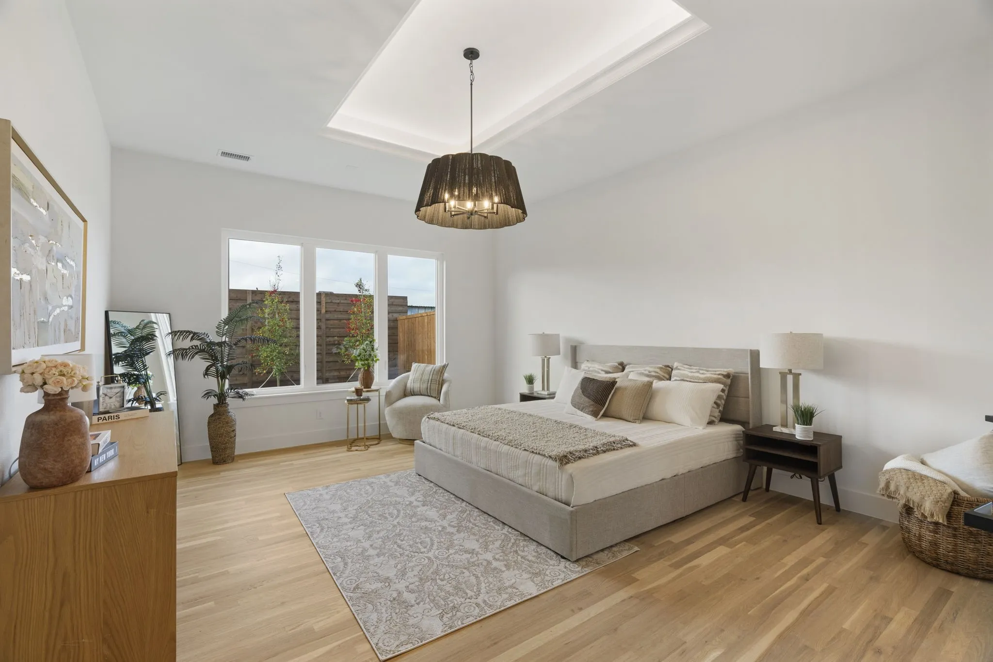 Bedroom featuring light wood finished floors, a raised ceiling, and hanging lights