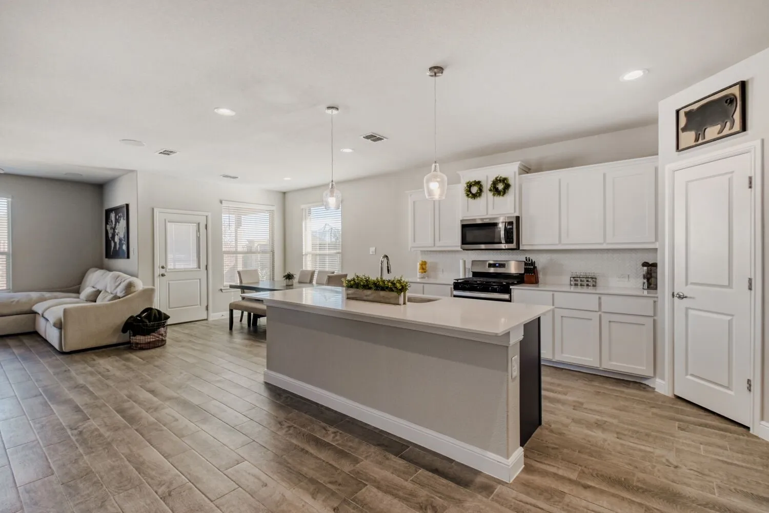 Kitchen with white cabinetry, hanging light fixtures, open floor plan, and stainless steel appliances