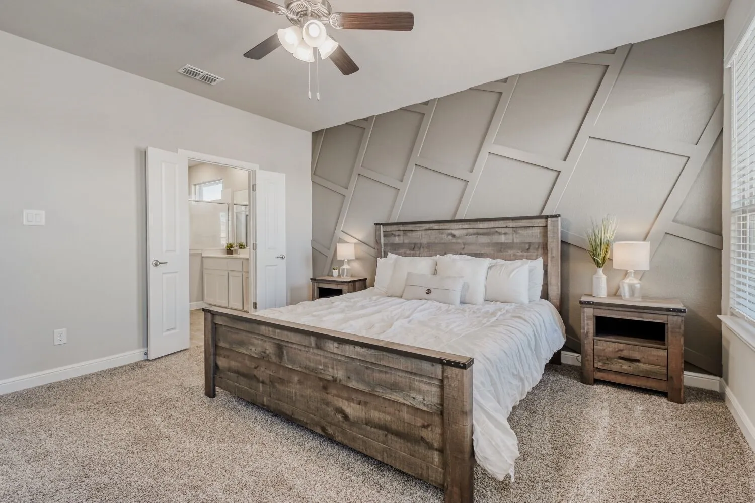 Bedroom featuring a decorative wall, light carpet, a ceiling fan, and connected bathroom