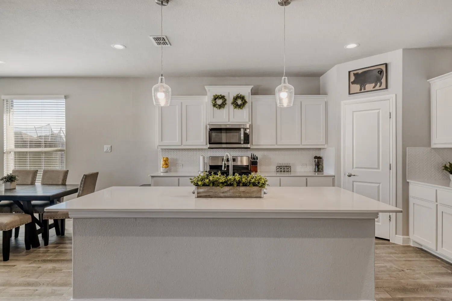 Kitchen featuring white cabinetry, pendant lighting, a kitchen island with sink, tasteful backsplash, and stainless steel appliances