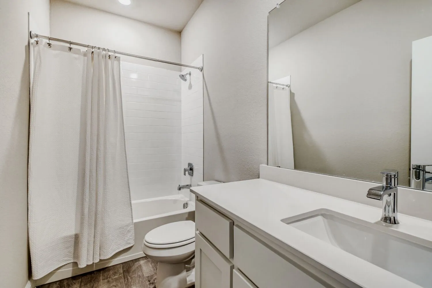 Bathroom with vanity, shower / tub combo with curtain, dark wood finished floors, and a textured wall
