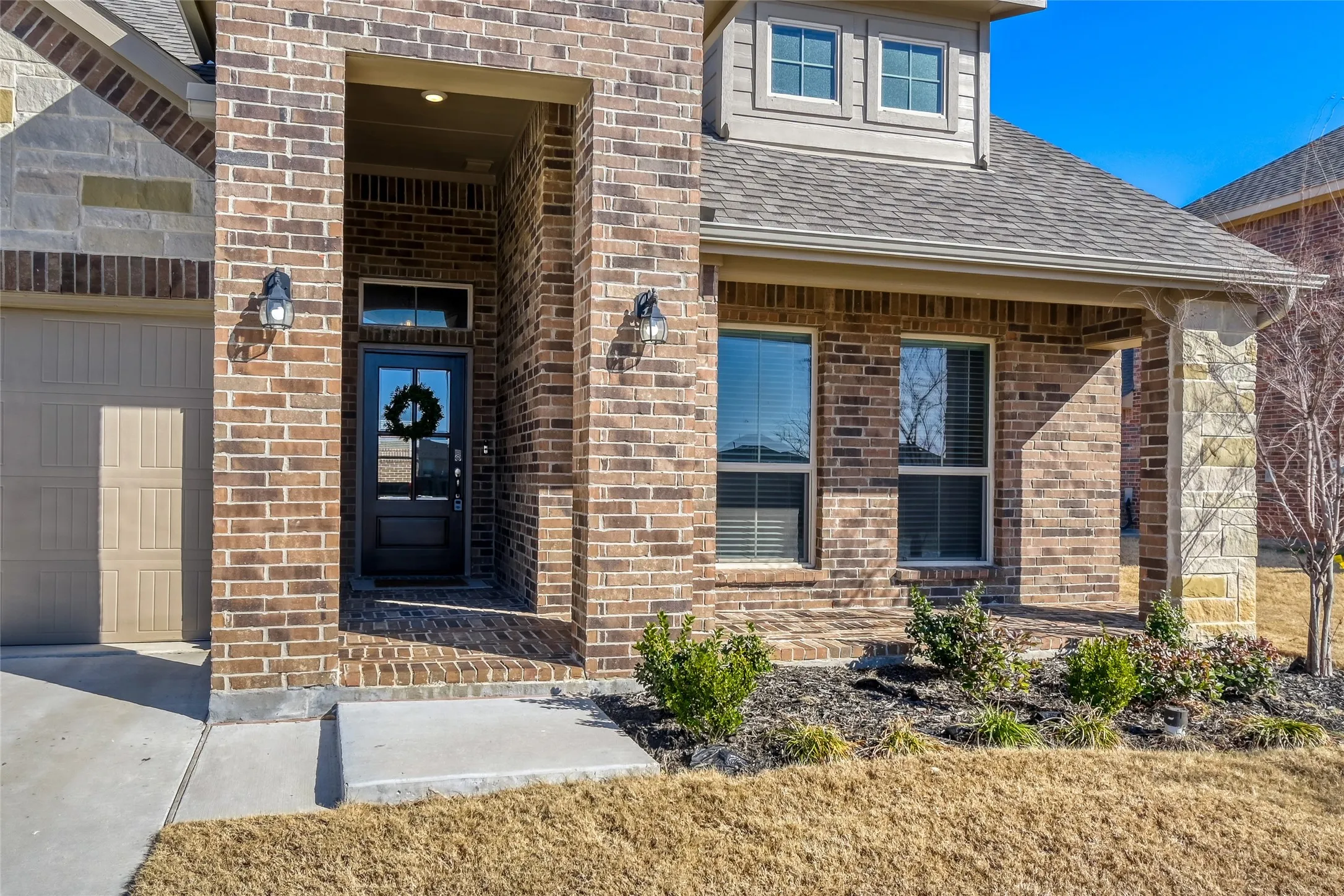 Doorway to property with brick siding, roof with shingles, and a garage