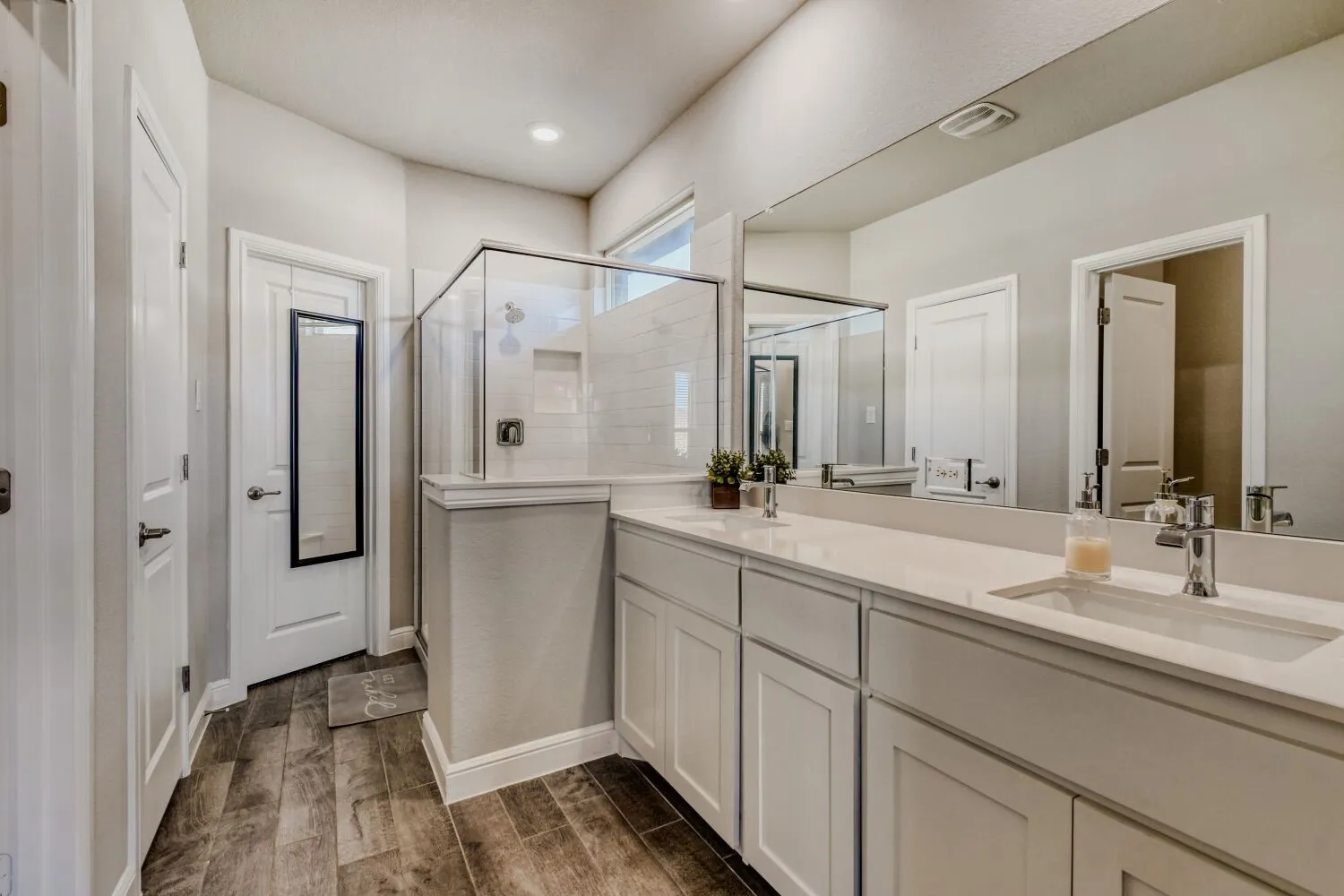 Bathroom featuring a stall shower, double vanity, and wood tiled floors