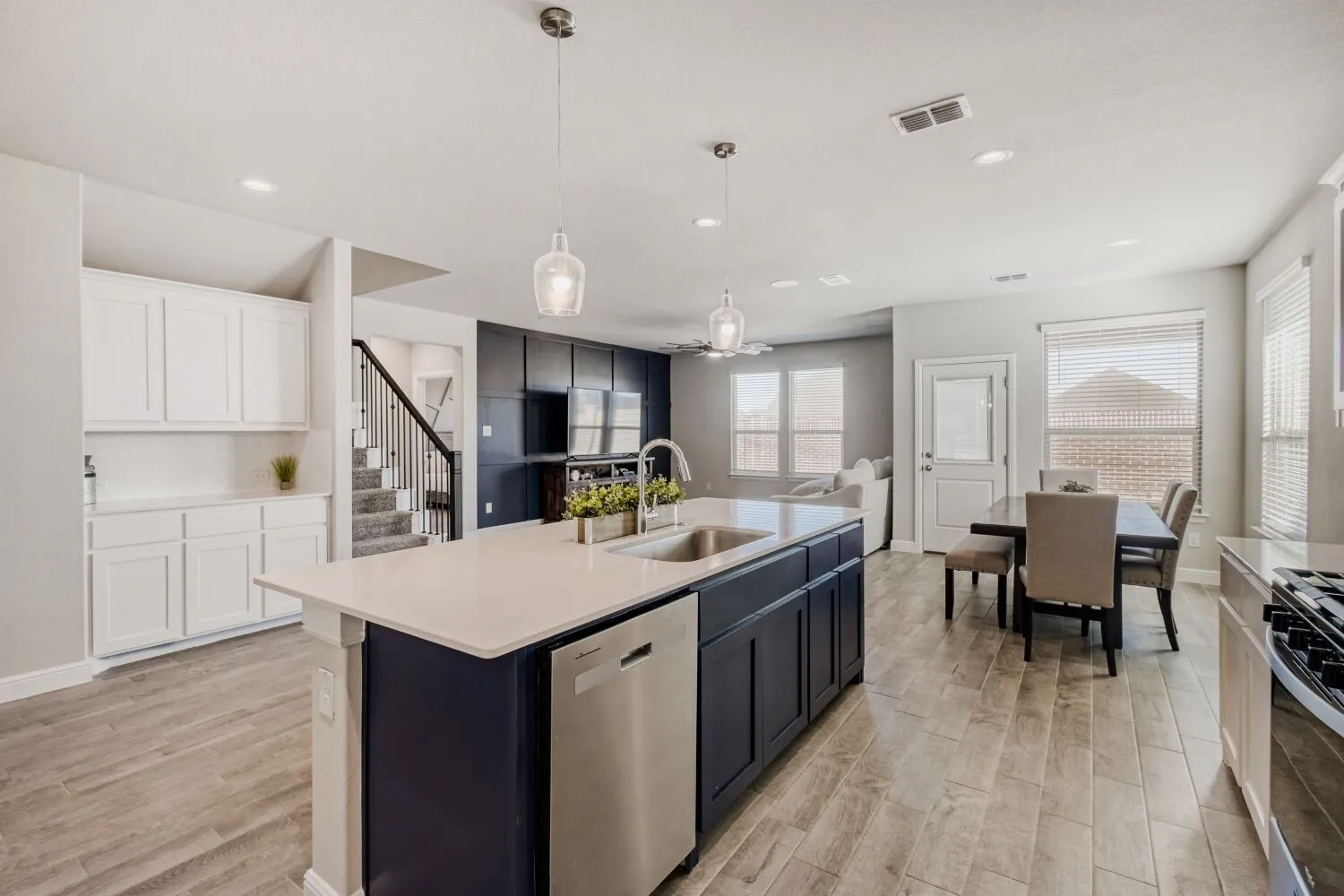 Kitchen featuring stainless steel appliances, pendant lighting, an island with sink, white cabinets, and open floor plan