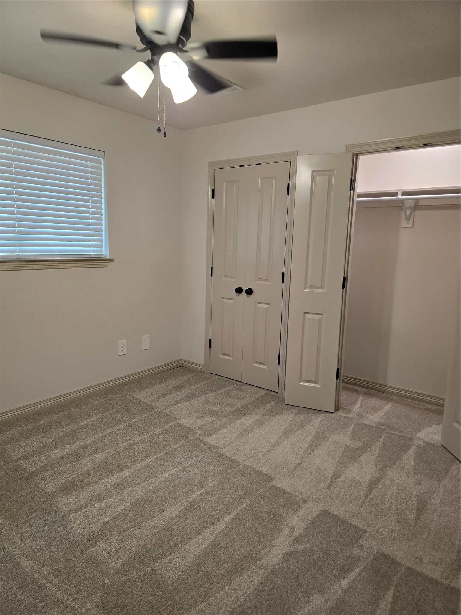 Bedroom with large closet, carpet, and ceiling fan