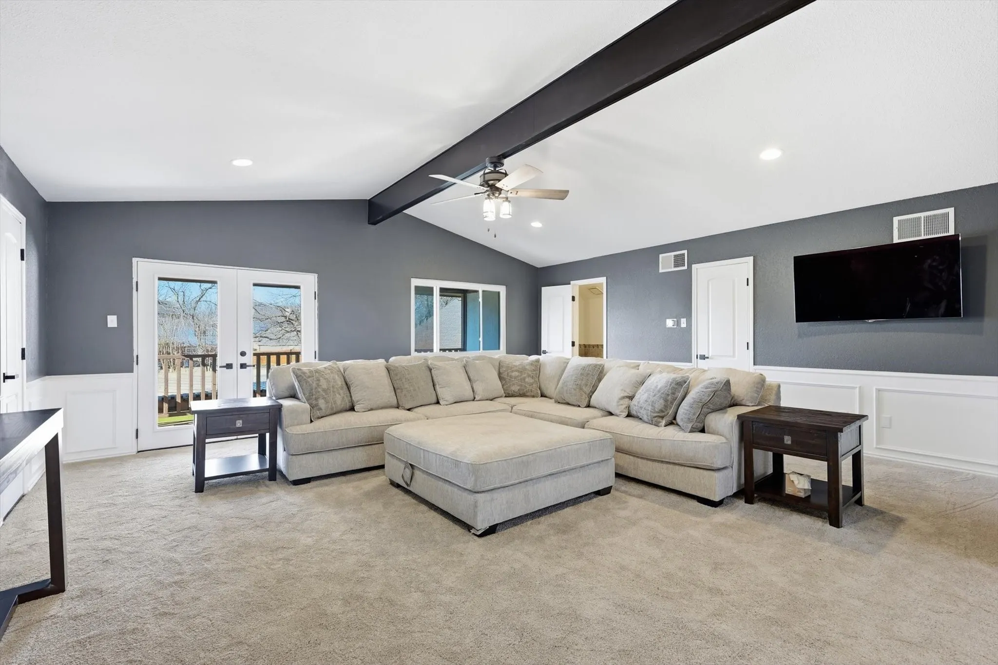 Living room with a decorative wall, wainscoting, carpet, french doors, and a ceiling fan