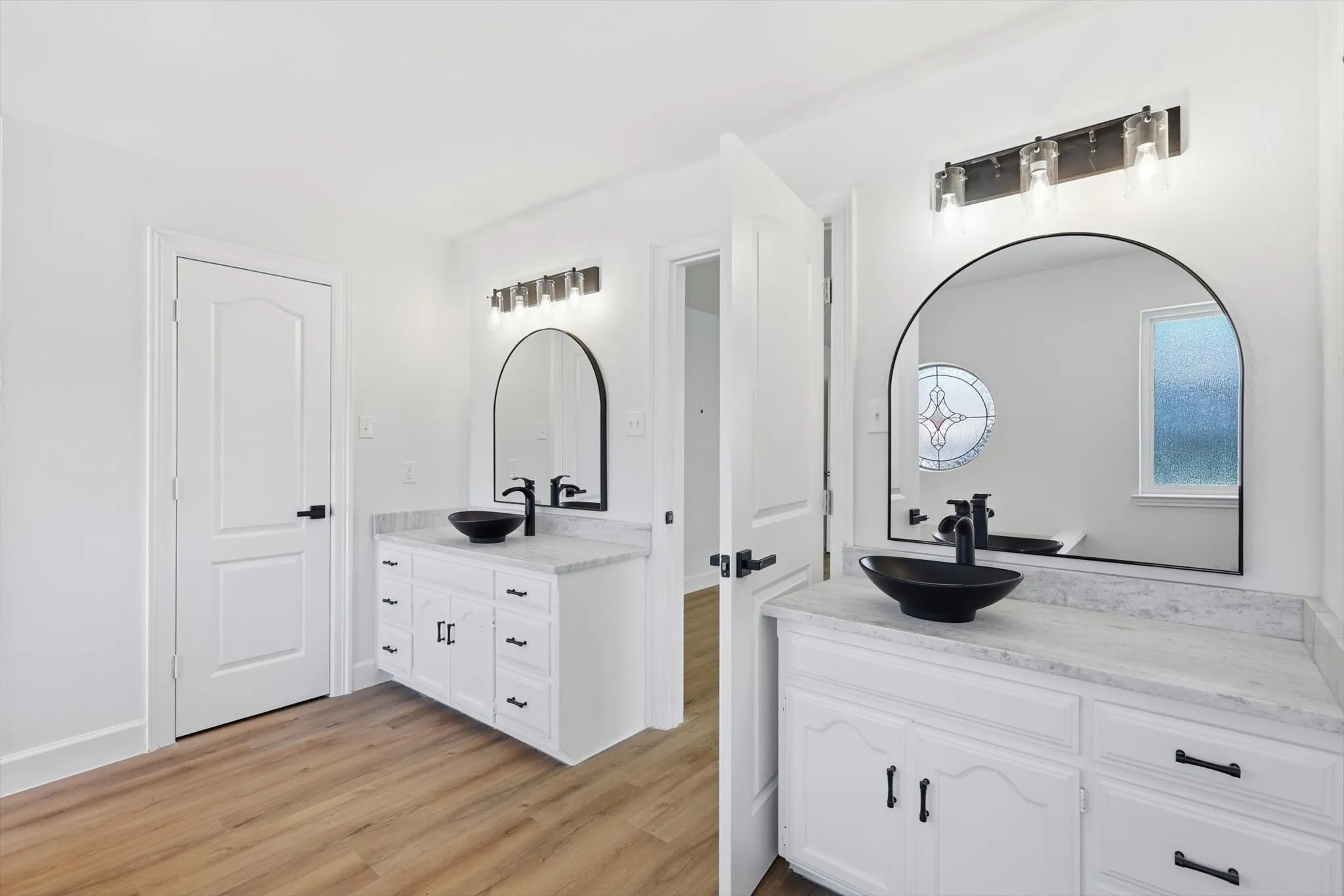 Full bathroom featuring two vanities and light wood finished floors