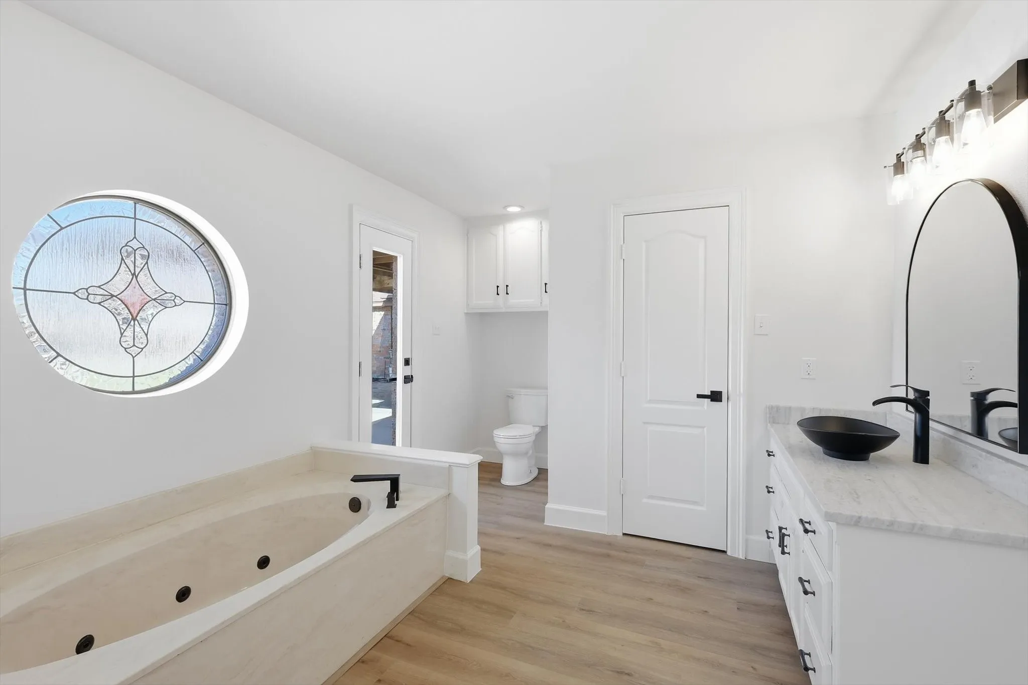 Full bathroom featuring vanity, a jetted tub, and light wood-style floors