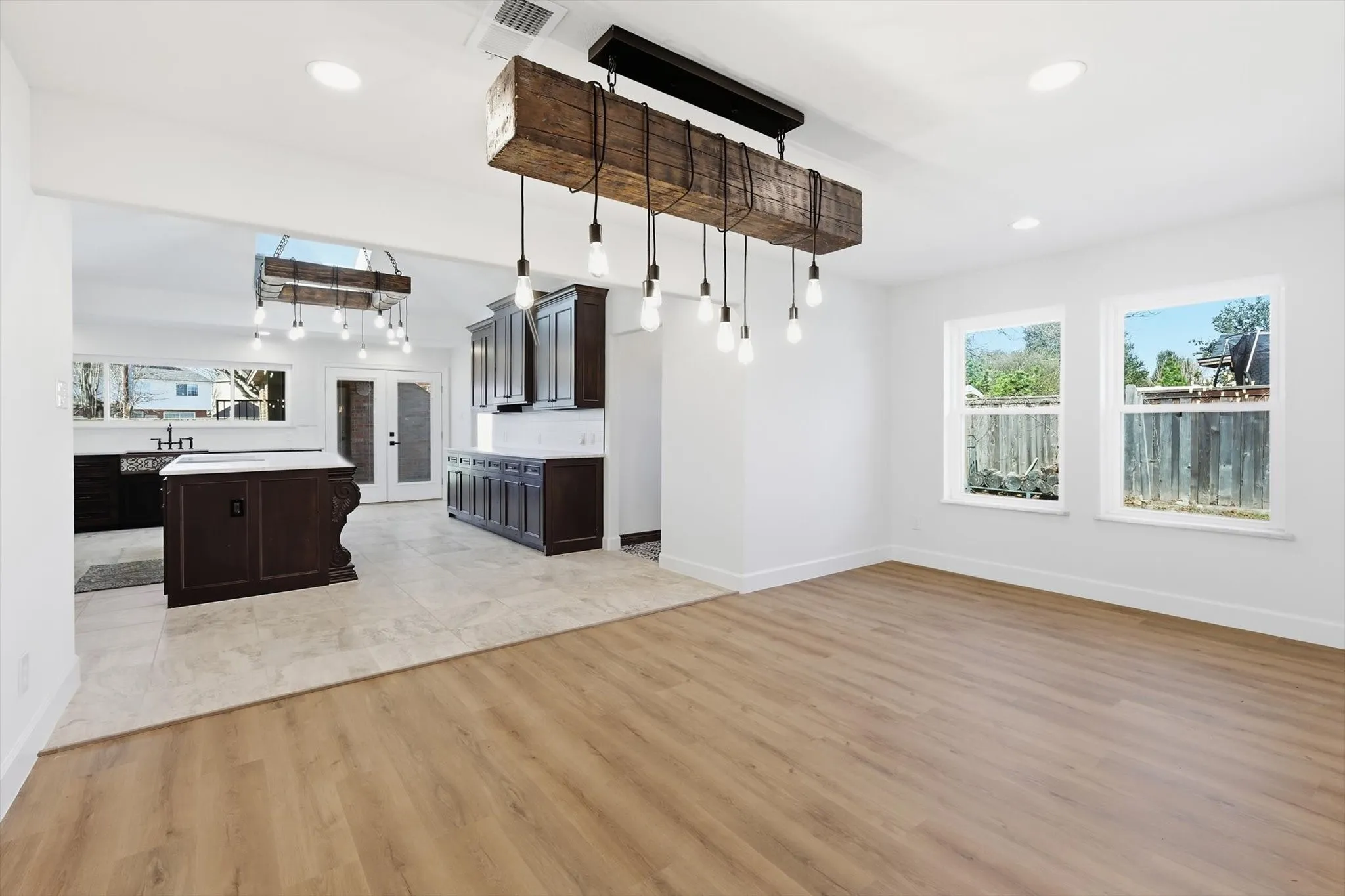 Kitchen featuring dark wood finish cabinets, open floor plan, french doors, light wood finished floors, and light countertops