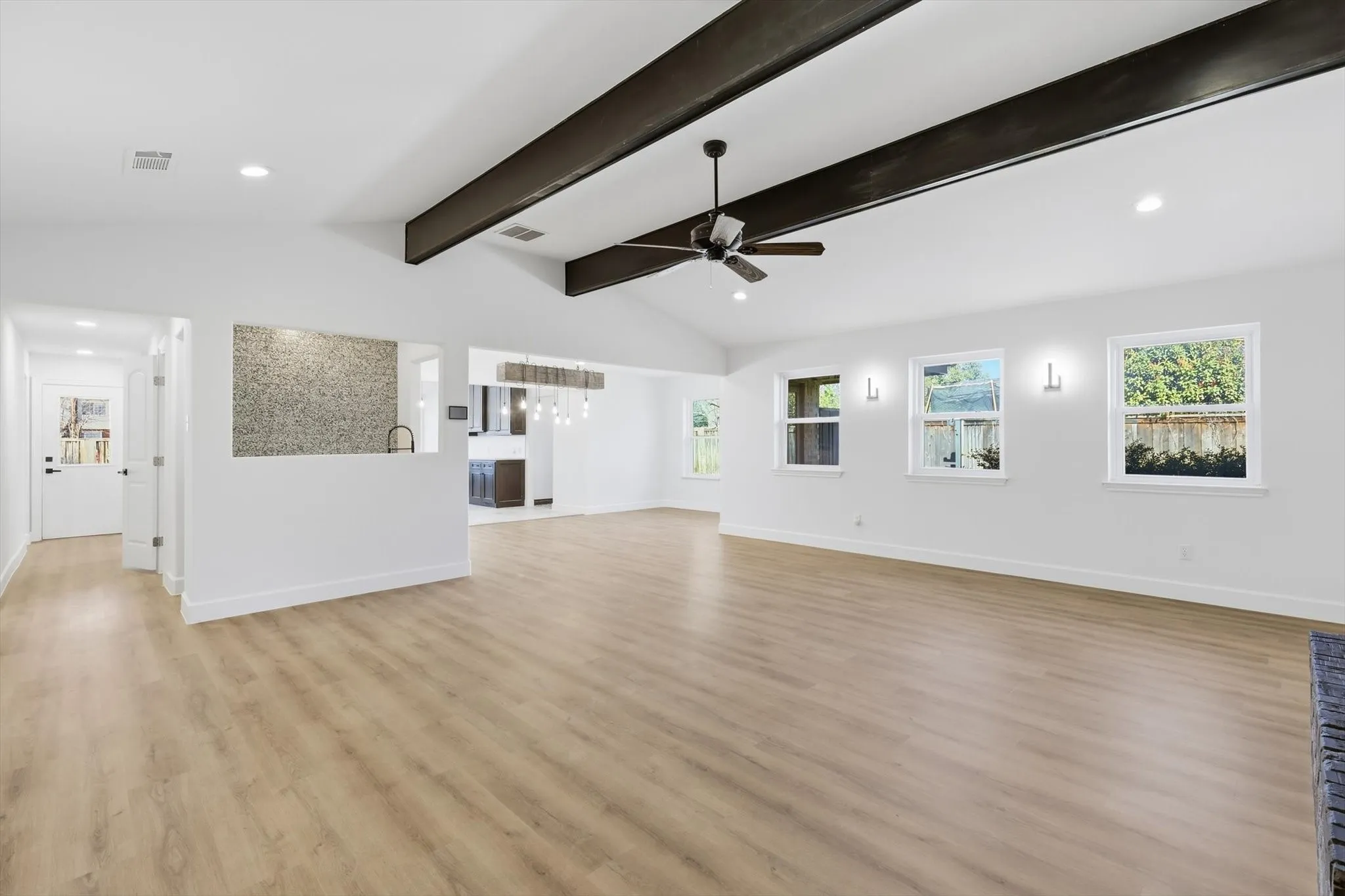 Unfurnished living room with recessed lighting, lofted ceiling with beams, light wood-style floors, and a ceiling fan